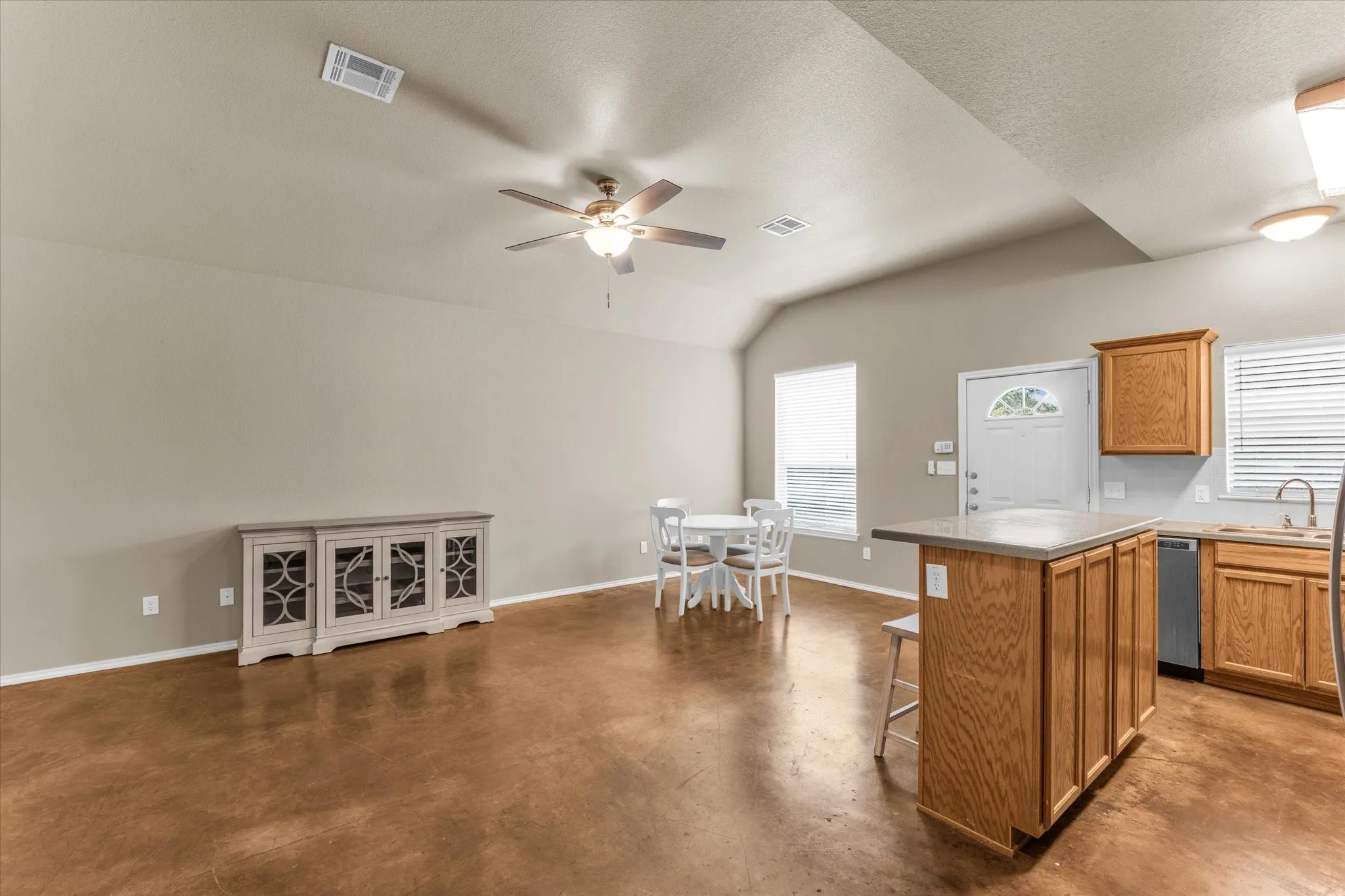 Open concept living space featuring a vaulted ceiling and rich, wood-finish flooring