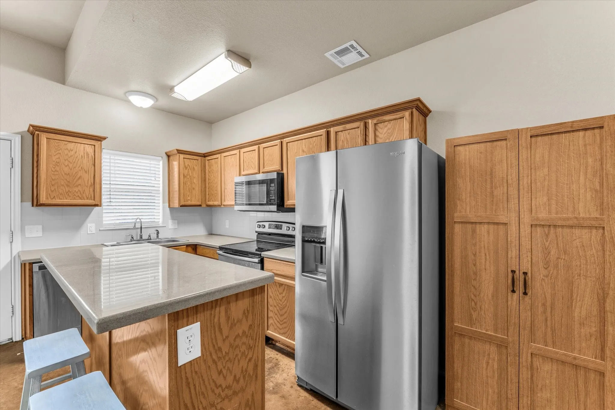 Kitchen with wood-finish cabinetry, stainless steel appliances, and an eat-at island