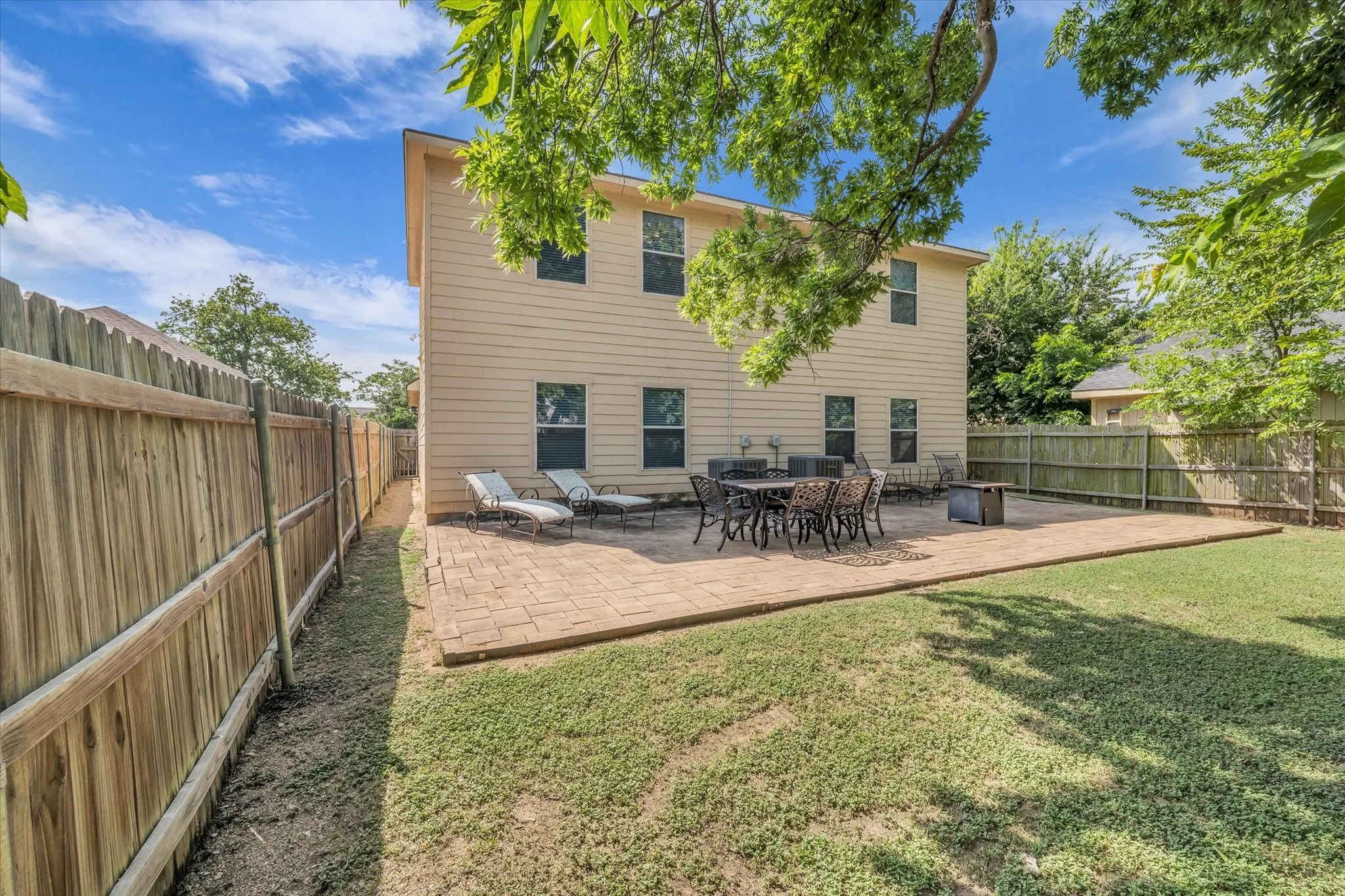 Spacious backyard featuring a rectangular paver patio, a manicured lawn, and wood privacy fencing