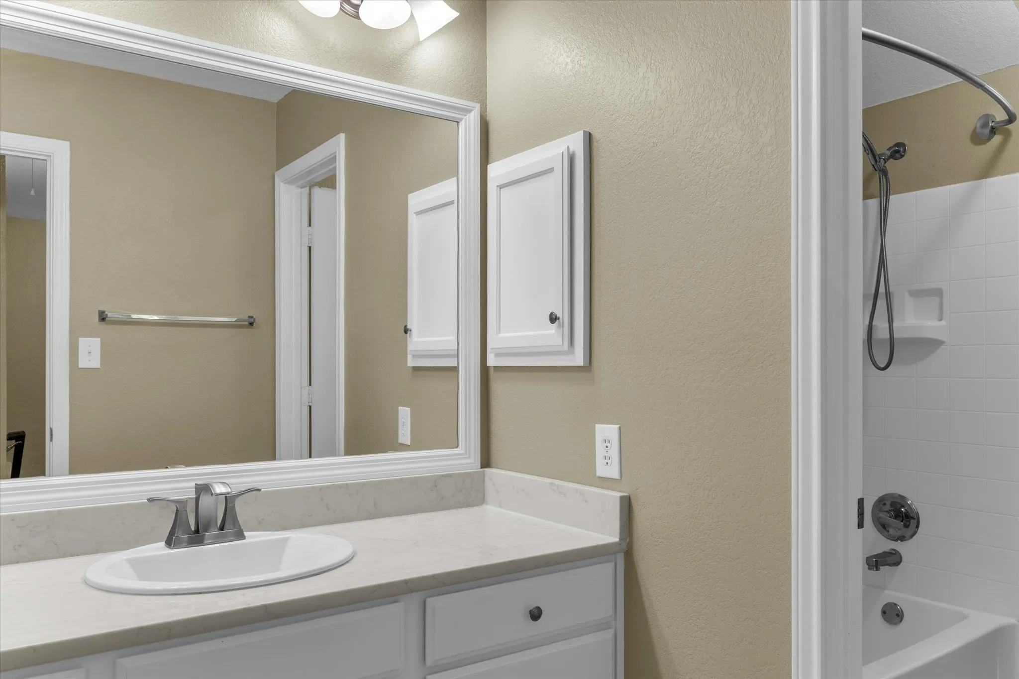 Bathroom featuring a white vanity with an integrated sink, a light-toned countertop, and white cabinetry