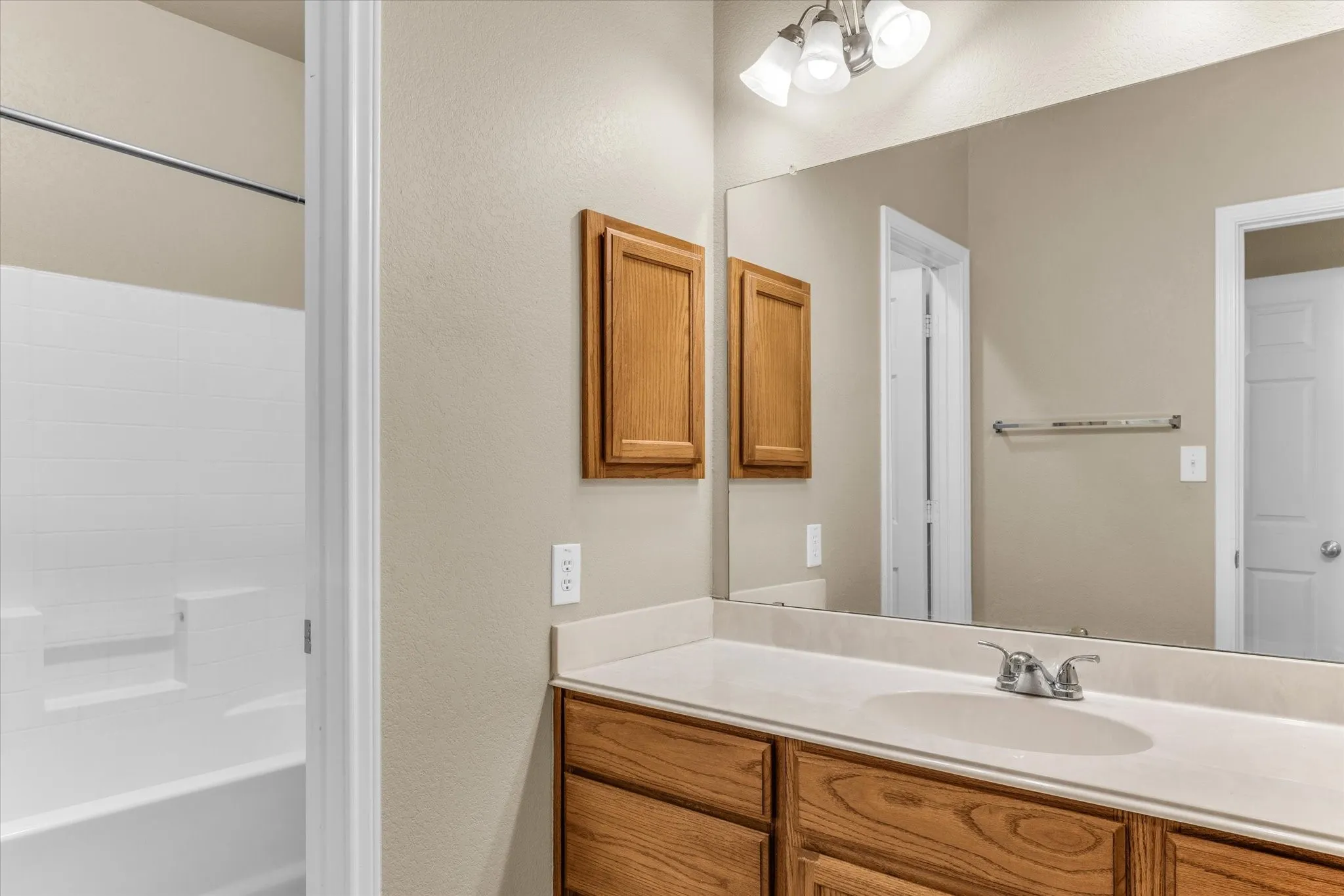 Bathroom featuring a single vanity with a white countertop, an undermount sink, and wood-finish cabinetry