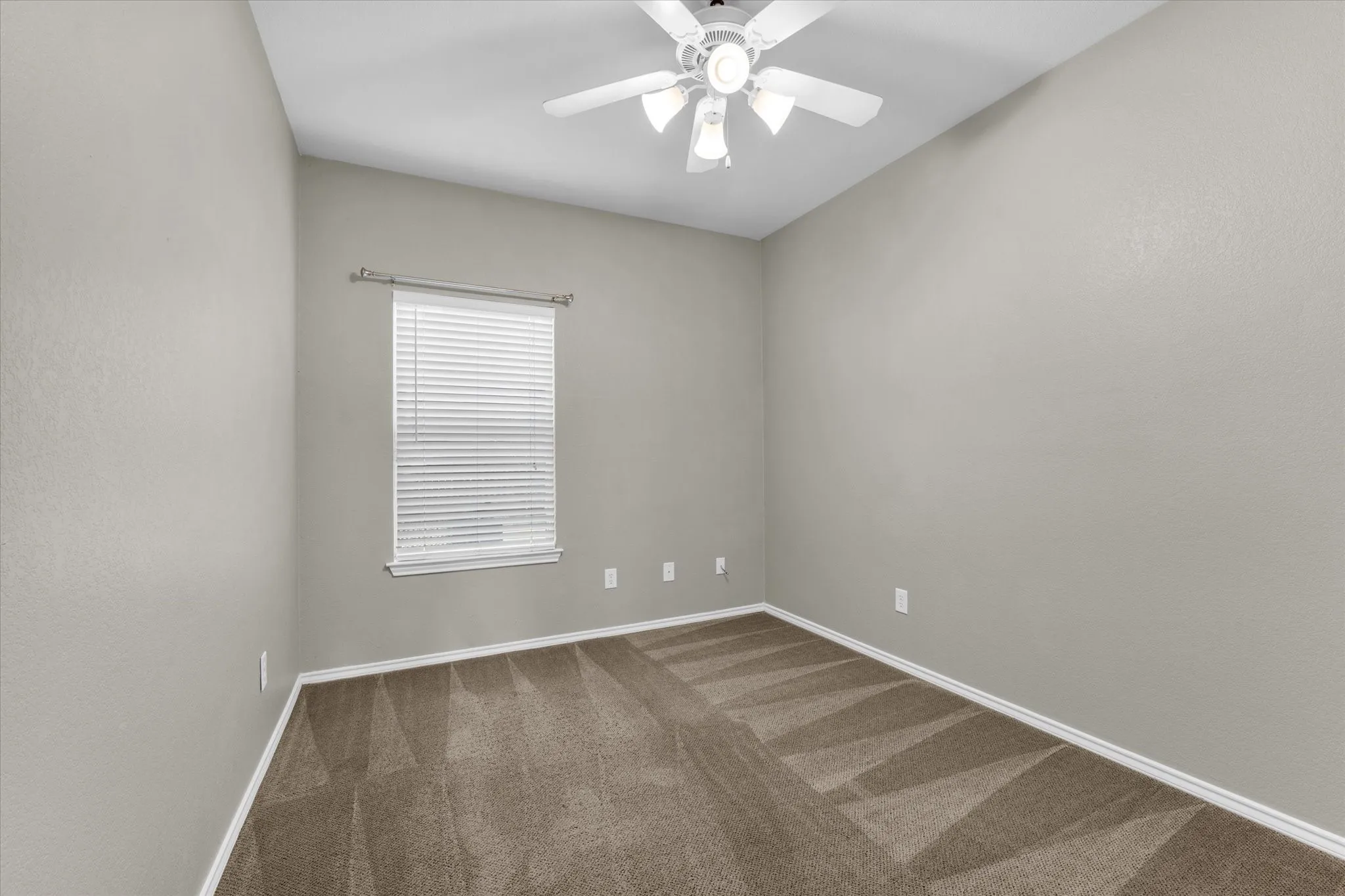 Room featuring neutral wall paint, a window with blinds, baseboards, and patterned carpet flooring