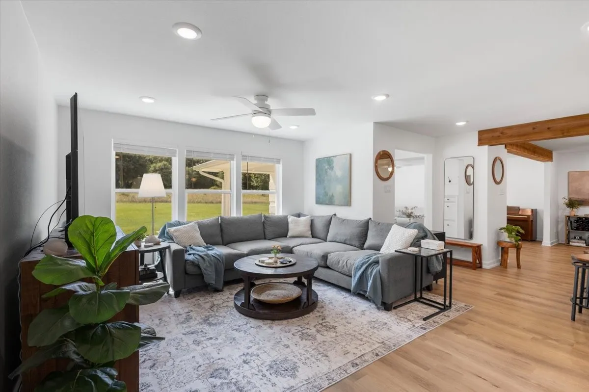 Spacious living area featuring light wood-finish flooring, recessed lighting, and a ceiling fan
