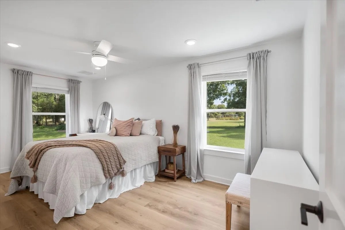 Bright Guest bedroom featuring light wood-finish flooring and a contemporary ceiling fan
