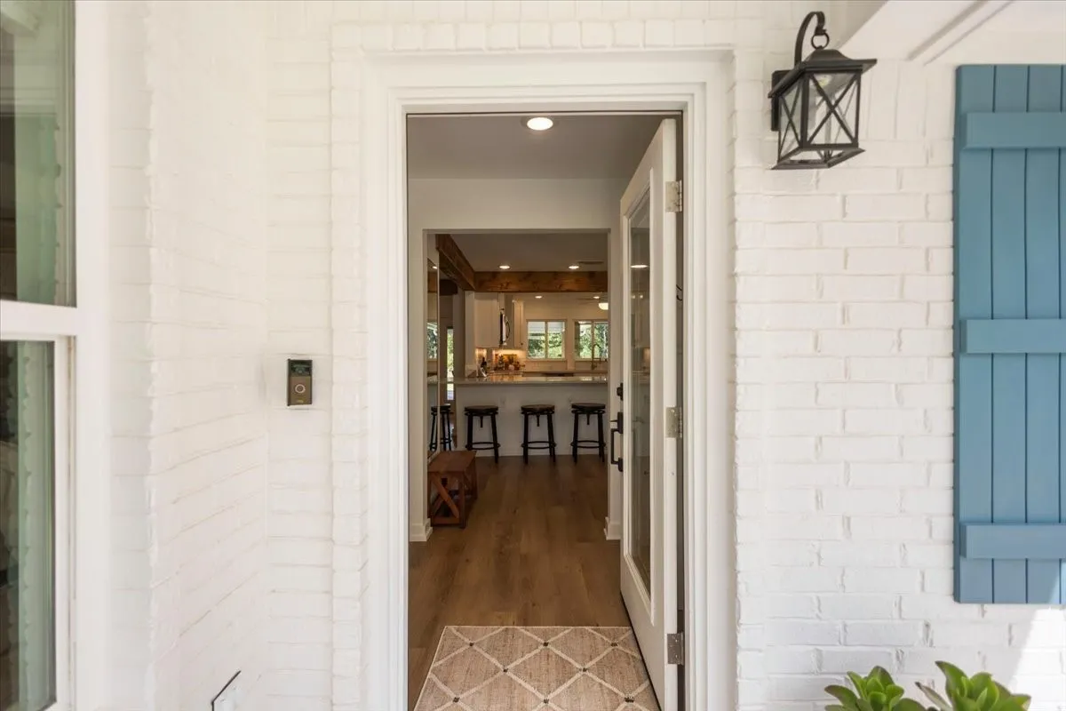 White painted brick exterior with a black lantern-style light fixture and blue decorative shutters