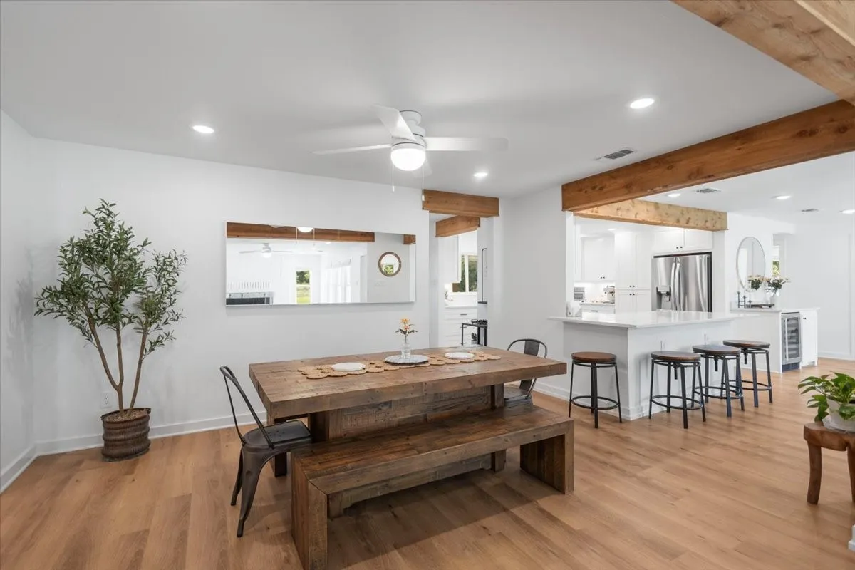 Bright interior featuring wood-finish flooring, exposed wood ceiling beams, recessed lighting, and a ceiling fan