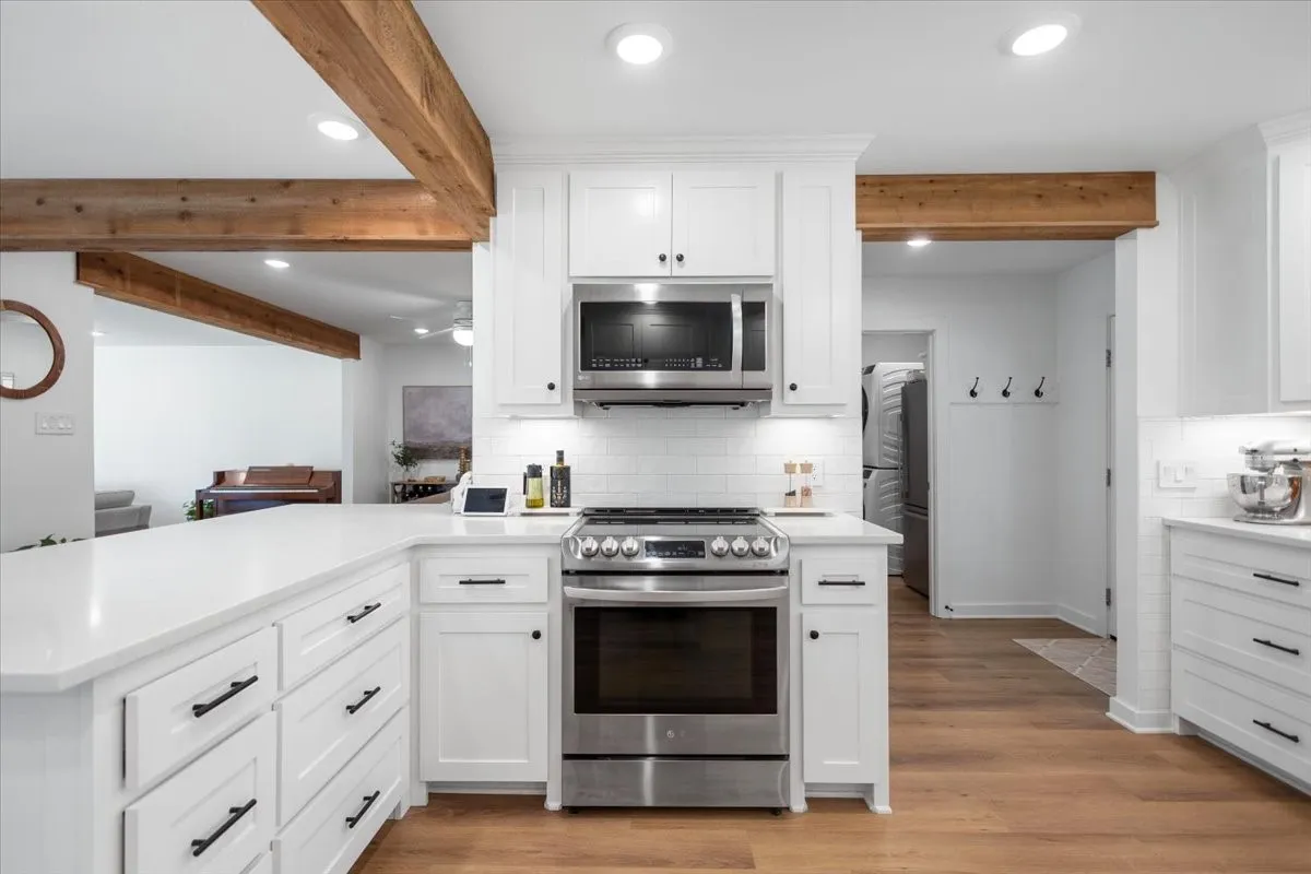 Modern kitchen featuring white cabinetry, stainless steel appliances, and wood-finish flooring