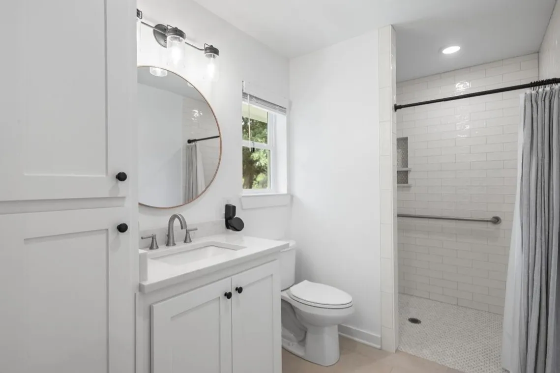 Guest Bathroom with White subway tile shower with a recessed niche, a grab bar, and a patterned tile floor