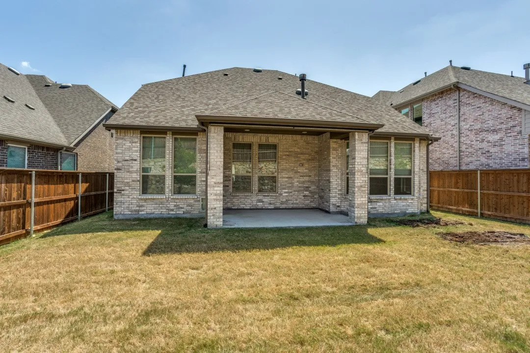 Brick exterior with a covered patio and a shingle roof