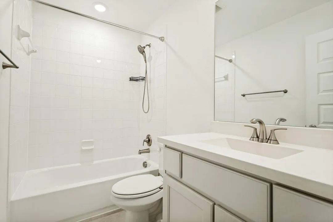 Light-filled bathroom featuring a single vanity with stone-finish countertop, undermount sink, and brushed nickel fixtures