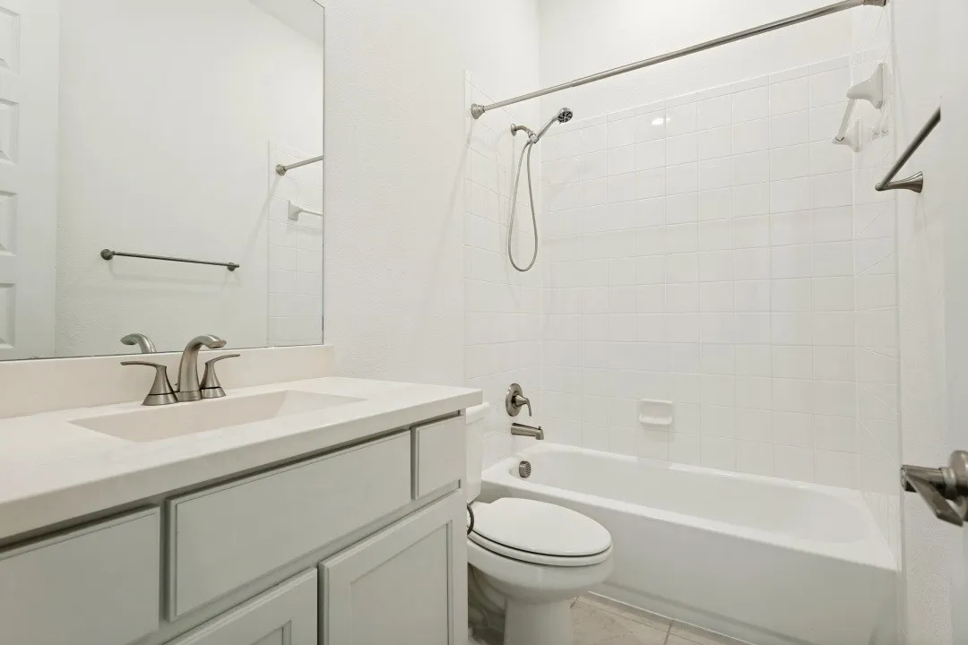 White vanity with a single basin sink, brushed nickel faucet, and a large wall mirror