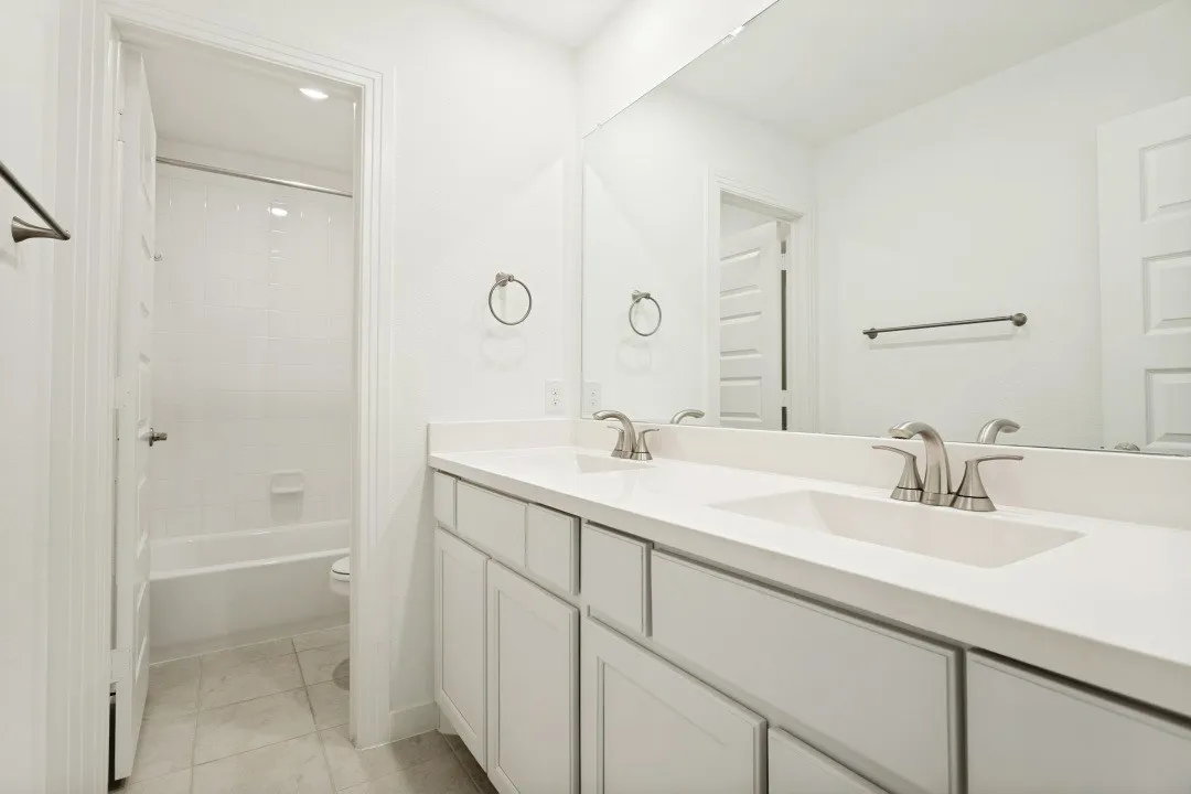 Dual vanity with integrated sinks, brushed nickel fixtures, and a large wall-mounted mirror