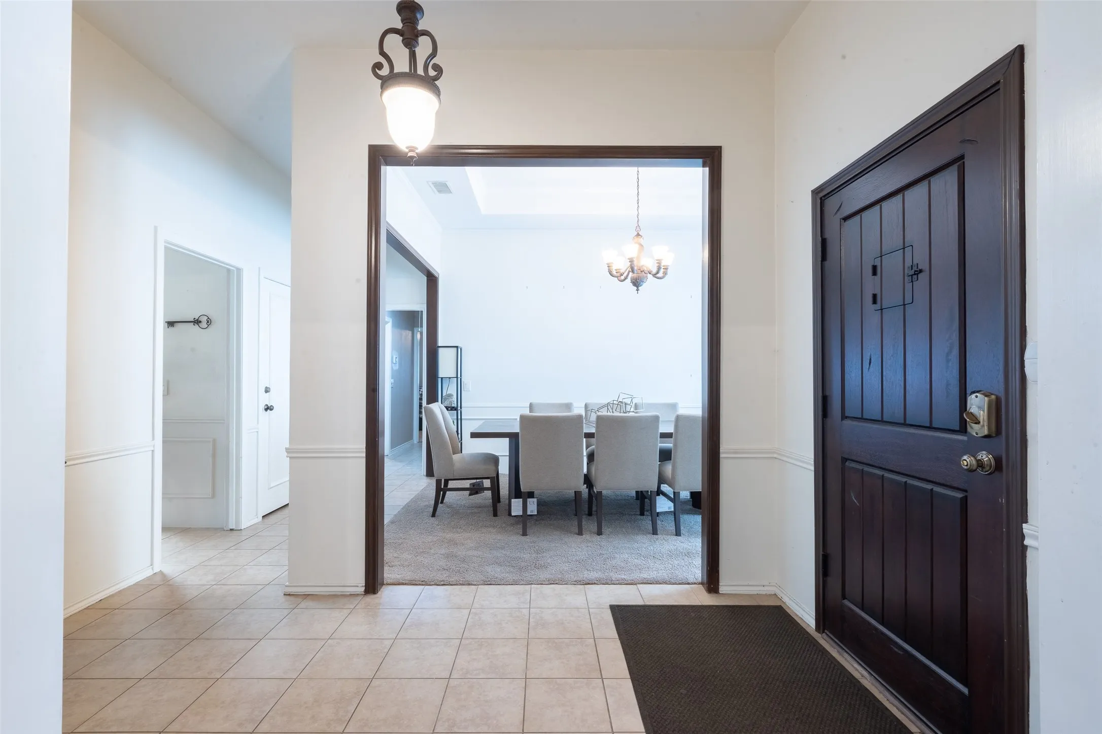 Entryway featuring neutral tile flooring, wainscoting, and a dark wood front door