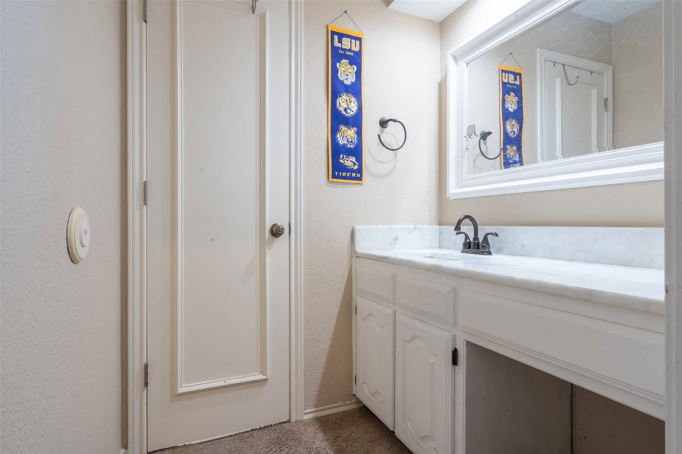 Bathroom vanity with white cabinetry, light-toned countertop, and a framed mirror