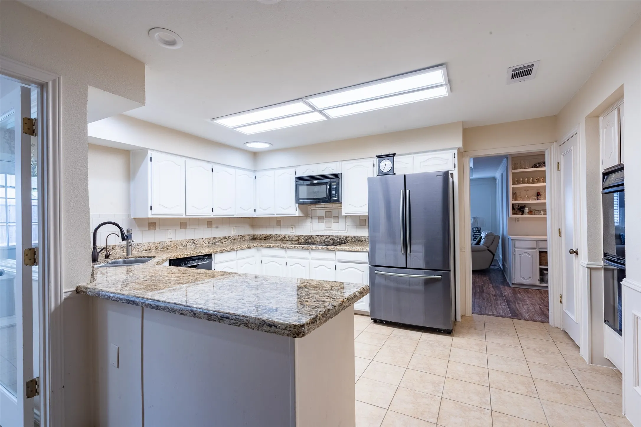Spacious kitchen featuring light-toned cabinetry, granite countertops, and tile flooring
