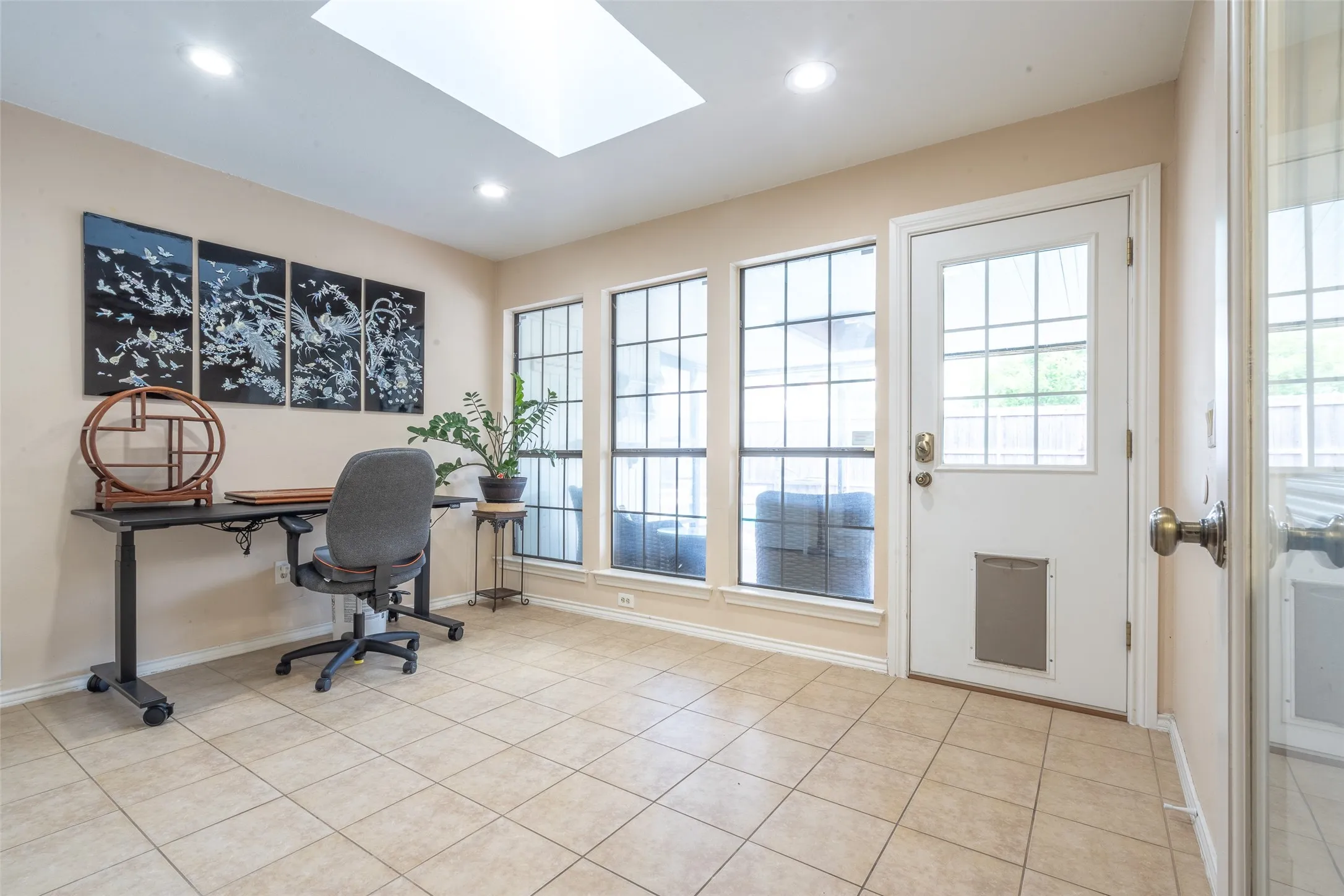 Tiled flooring throughout this versatile room, featuring a skylight and recessed lighting