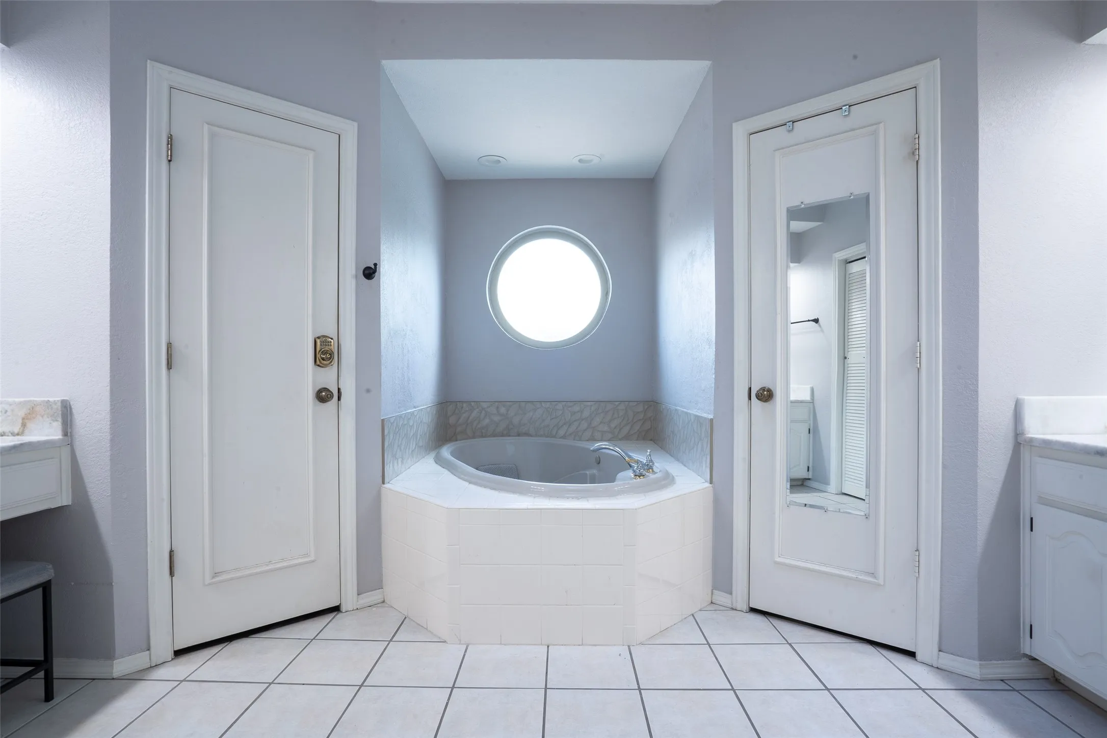 Corner soaking tub with a circular window, flanked by two doors