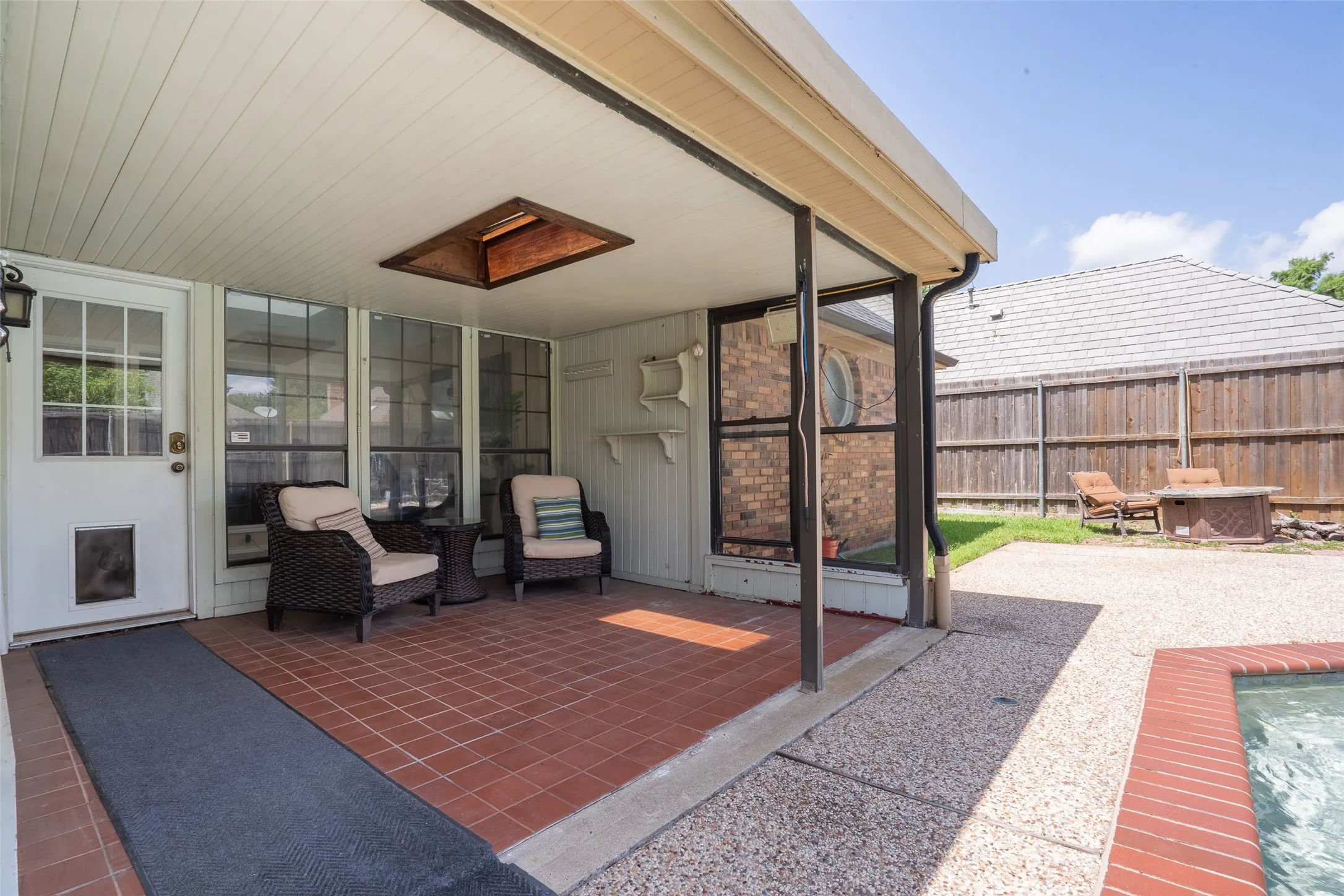 Covered patio featuring red brick-style tile flooring, an overhead skylight, and a white paneled ceiling
