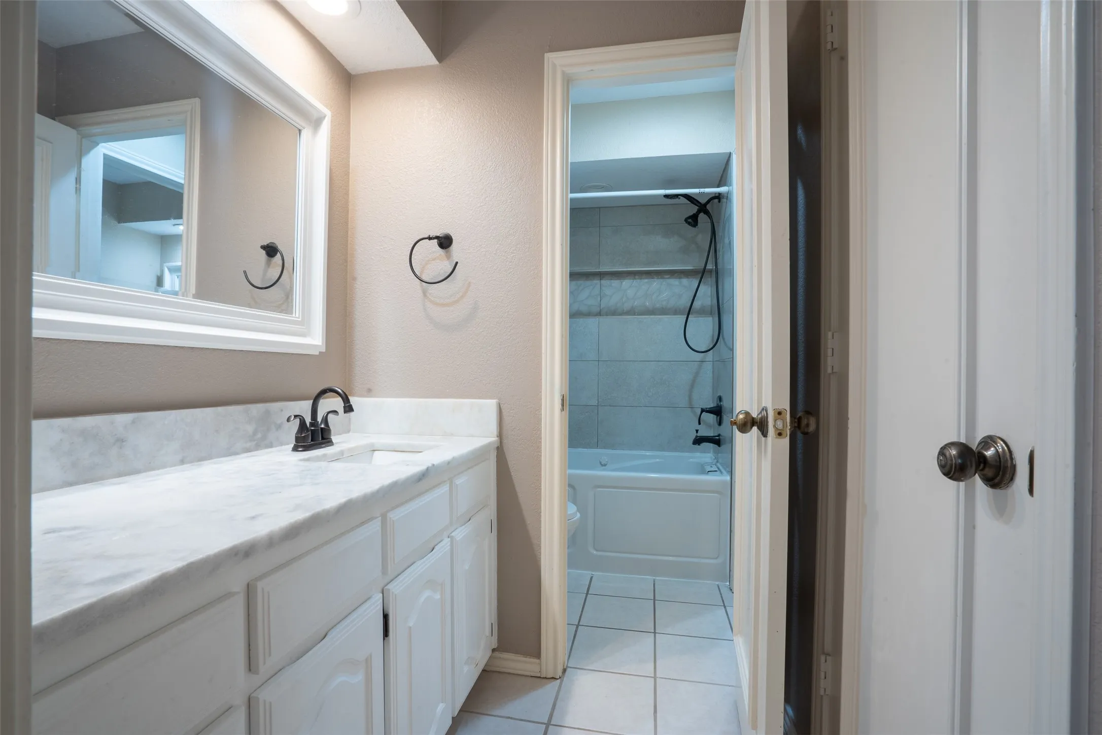 Bathroom vanity featuring a white countertop with integrated sink, dark bronze-finish faucet, and recessed lighting