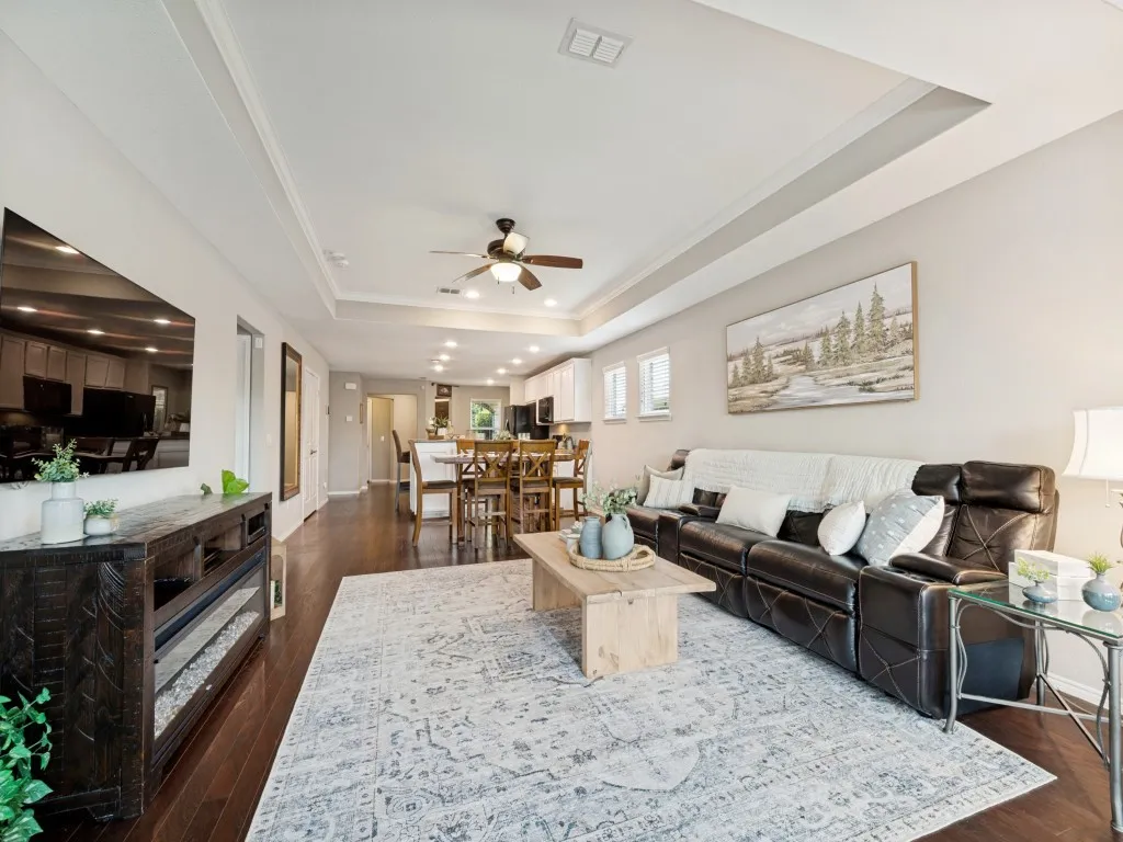 Expansive living area with wood-finish flooring, recessed lighting, and tray ceilings