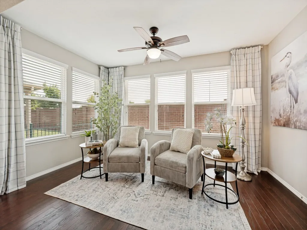 Spacious room featuring multiple windows with blinds, wood-finish flooring, and a ceiling fan with integrated lighting