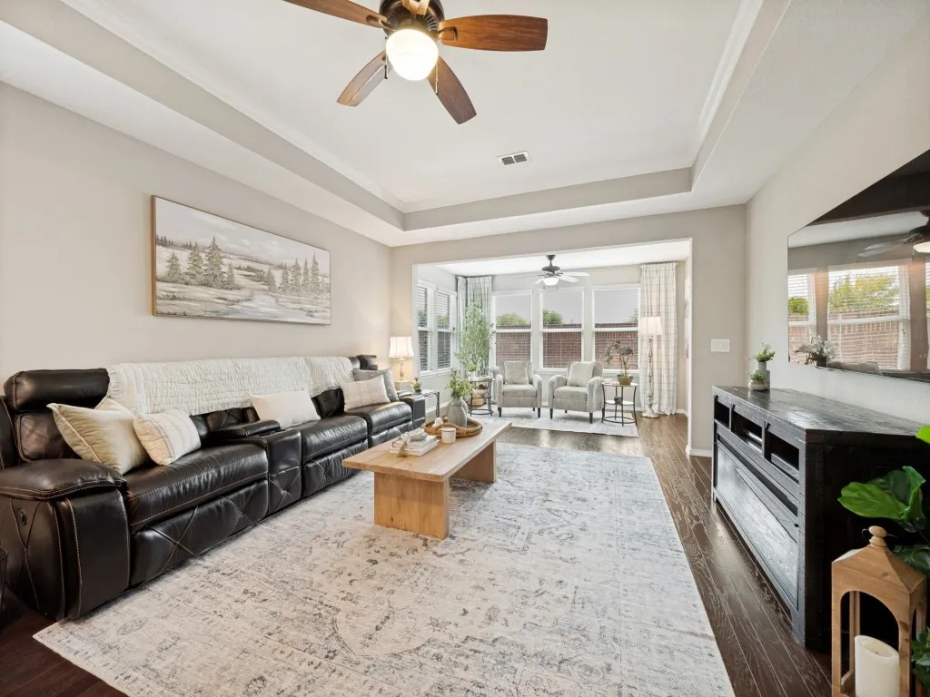 Open-concept living space with dark wood-finish flooring, a tray ceiling, and a ceiling fan