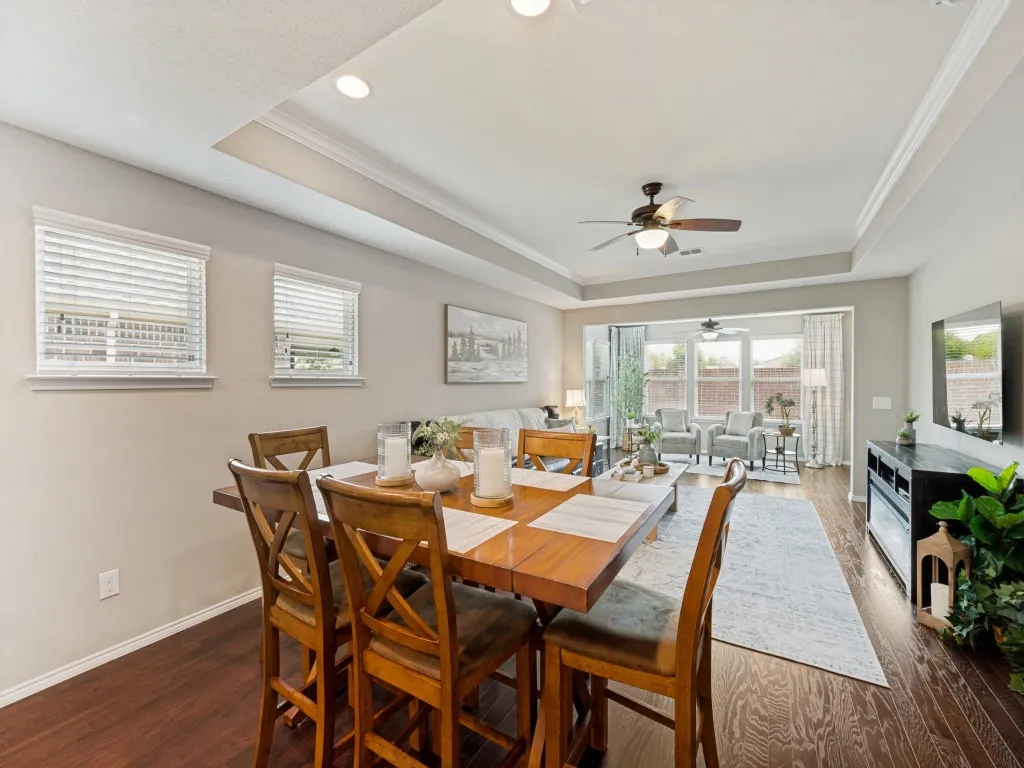 Open-concept living space featuring wood-finish flooring, recessed lighting, and a tray ceiling