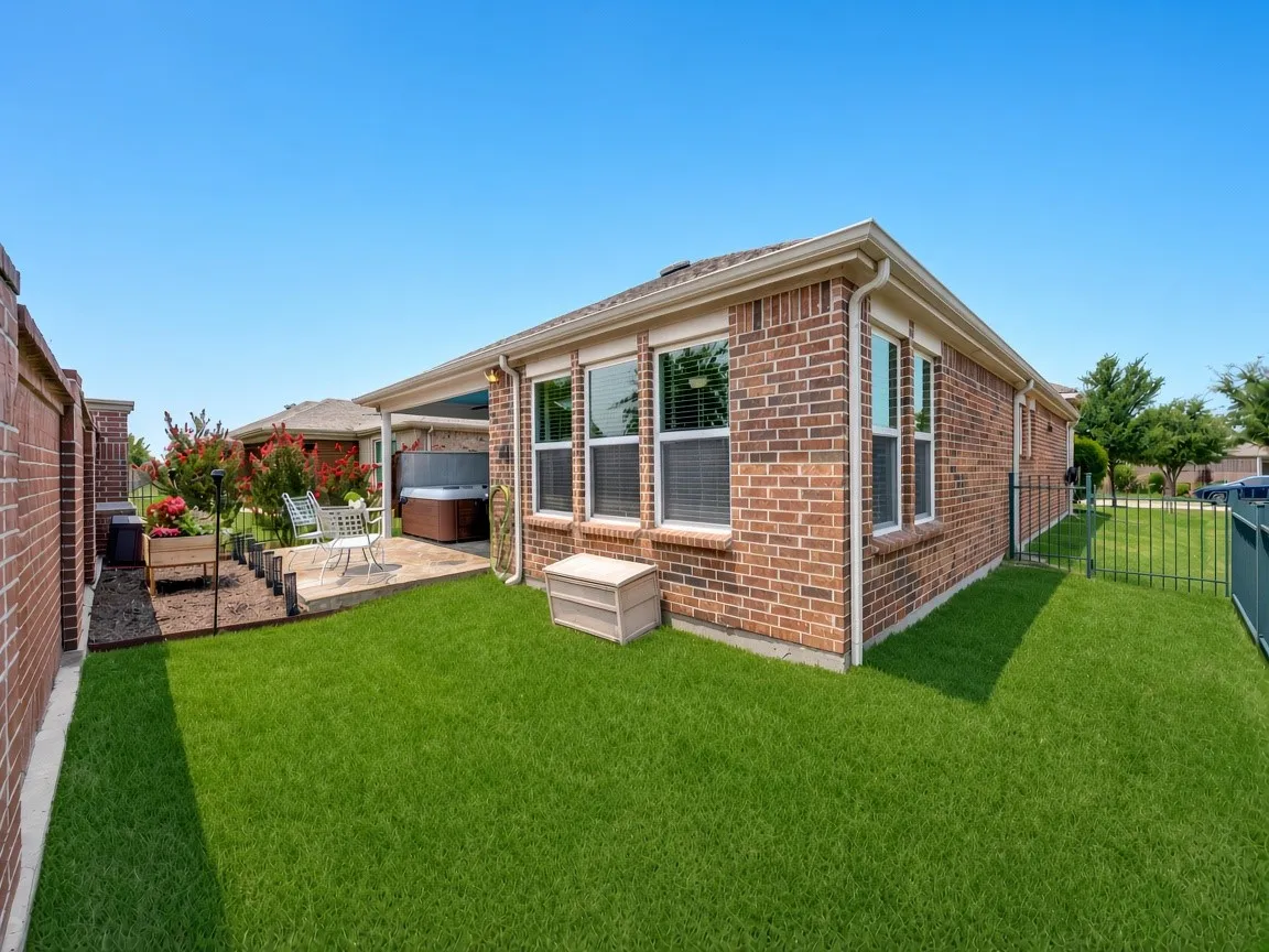 Exterior brick facade with multiple windows and an extended covered patio.  Grass has been digitally enhanced.