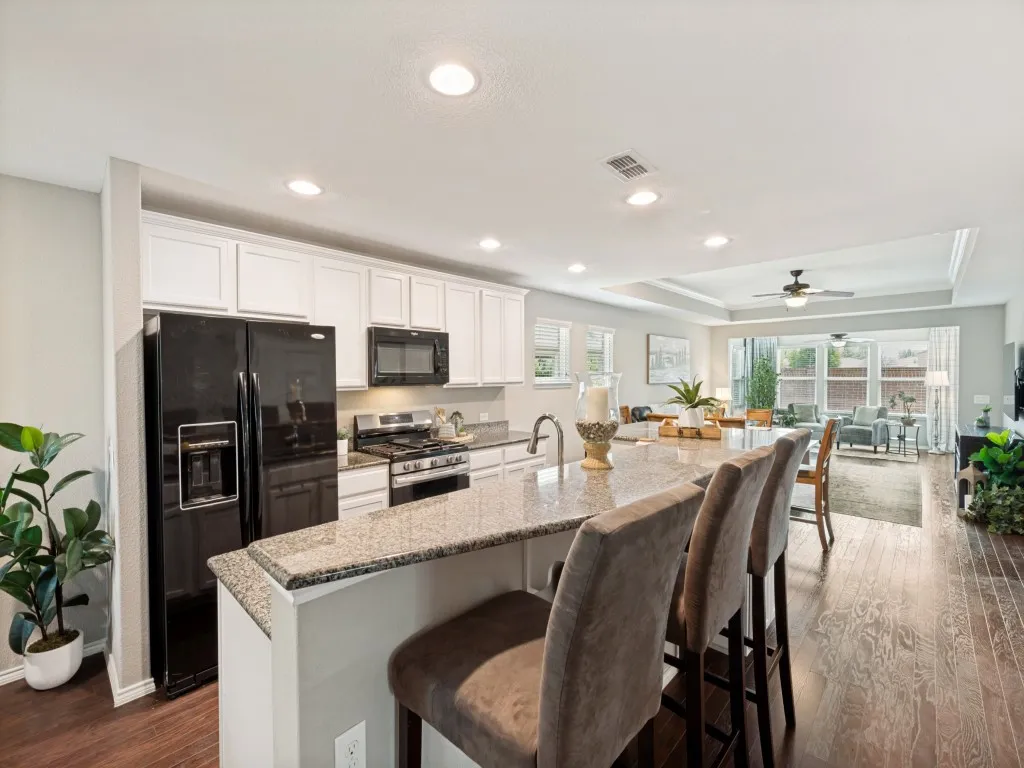 Kitchen featuring an extended island with a stone-finish countertop, white cabinetry, recessed lighting, and wood-finished flooring