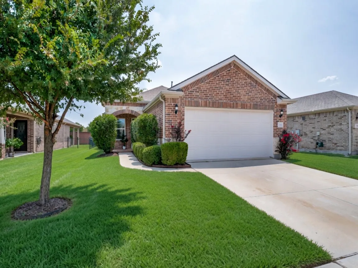 Brick exterior with stone accents, a two-car garage, and an arched entry.  Grass has been digitally enhanced.