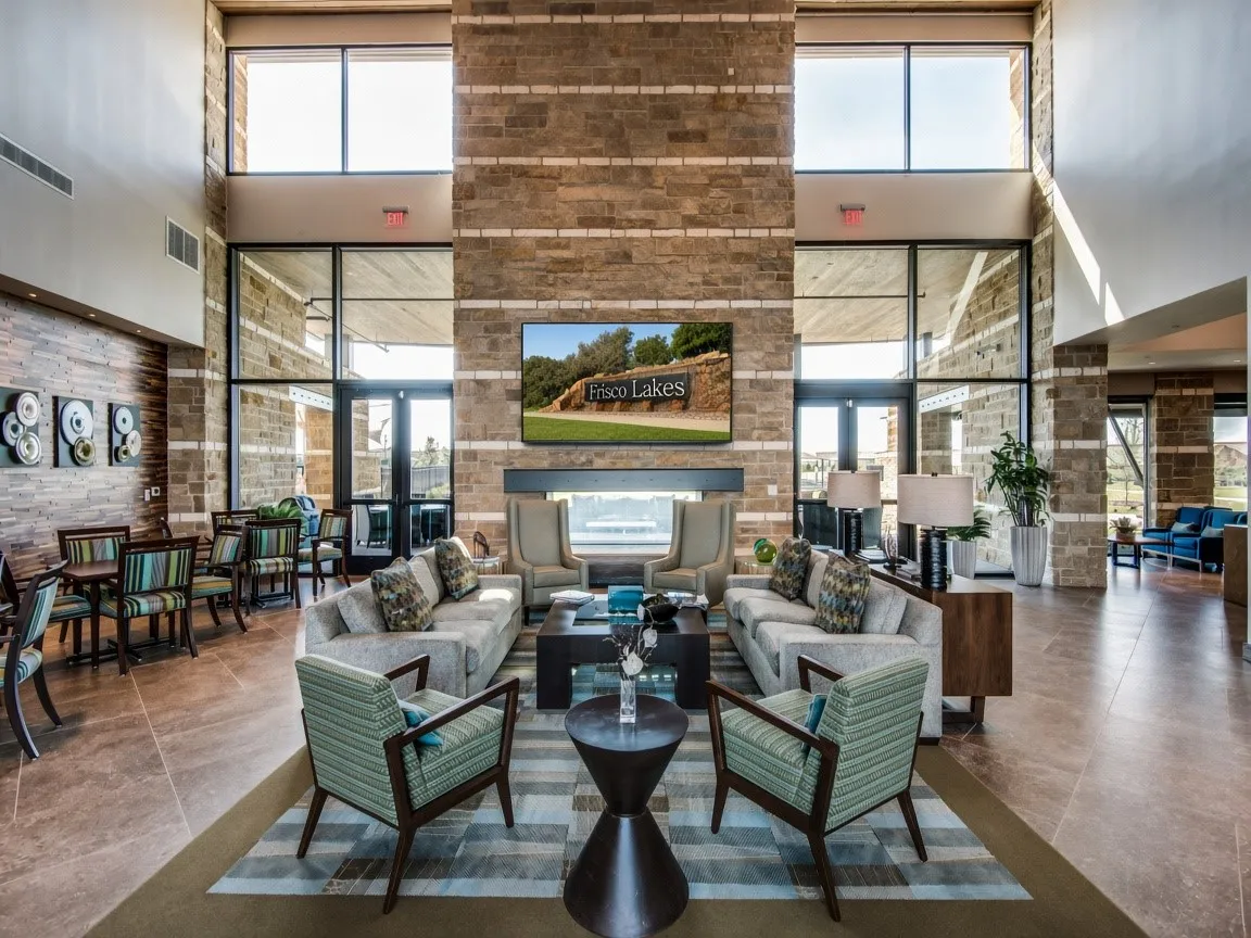 Two-story stone wall with integrated fireplace, expansive floor-to-ceiling windows, and tile flooring