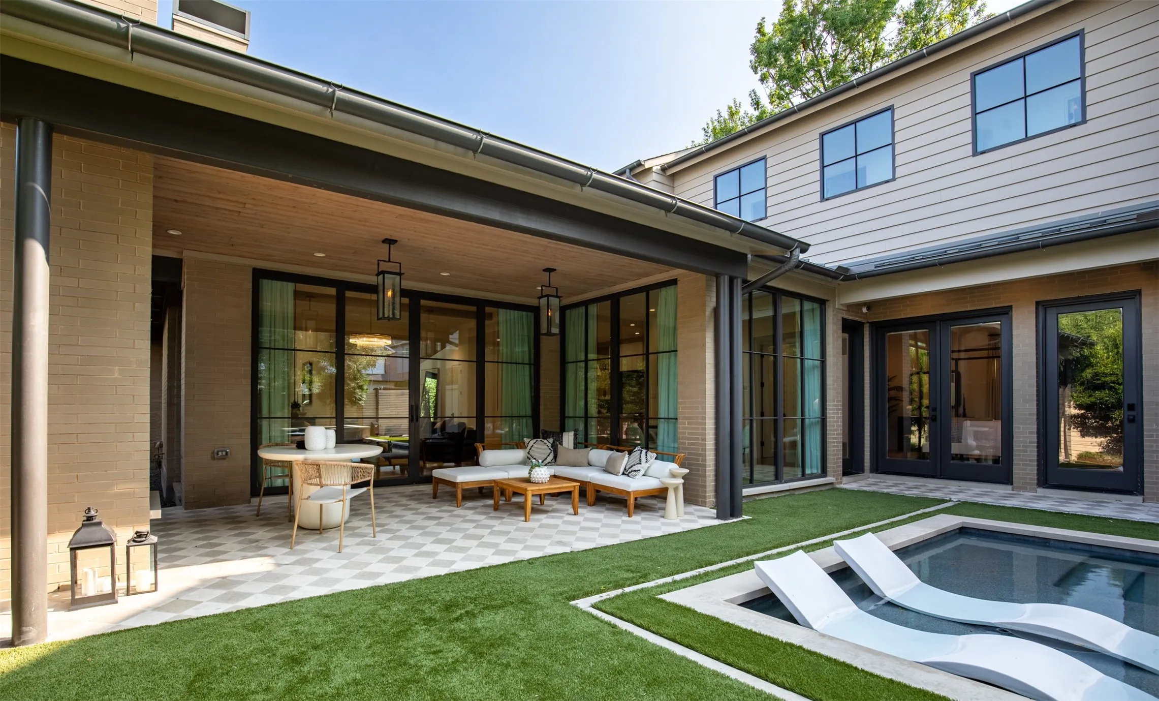 Covered patio with a patterned tile surface, recessed lighting, and wall-mounted lanterns
