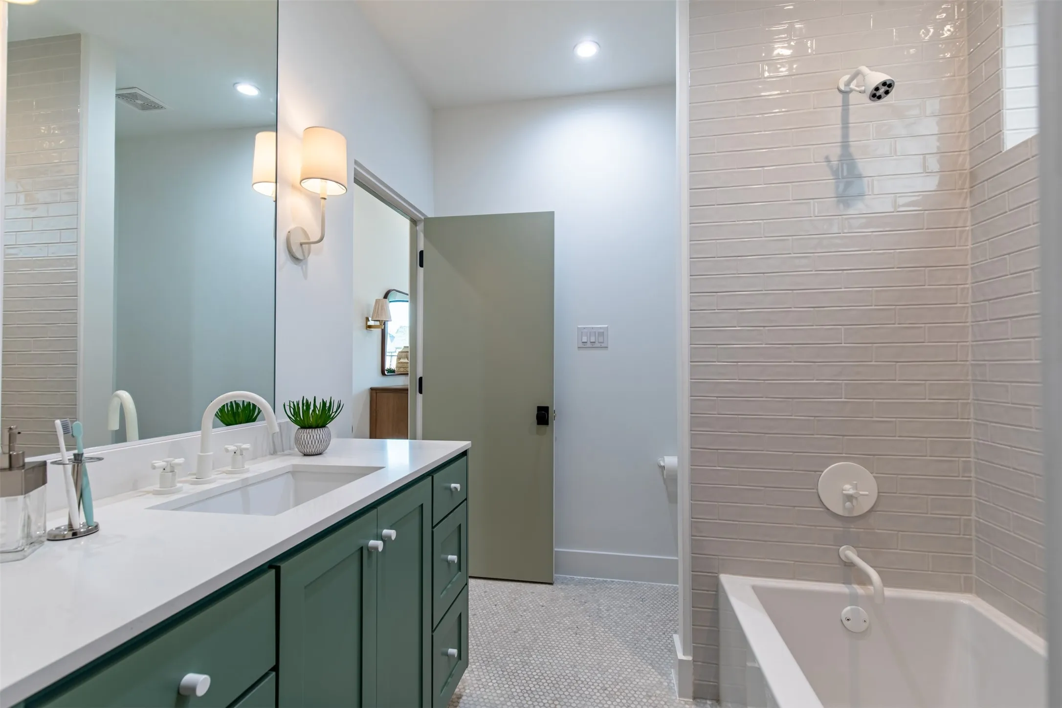 Bathroom featuring a deep green vanity with white knobs, a white countertop with an integrated sink, and white fixtures