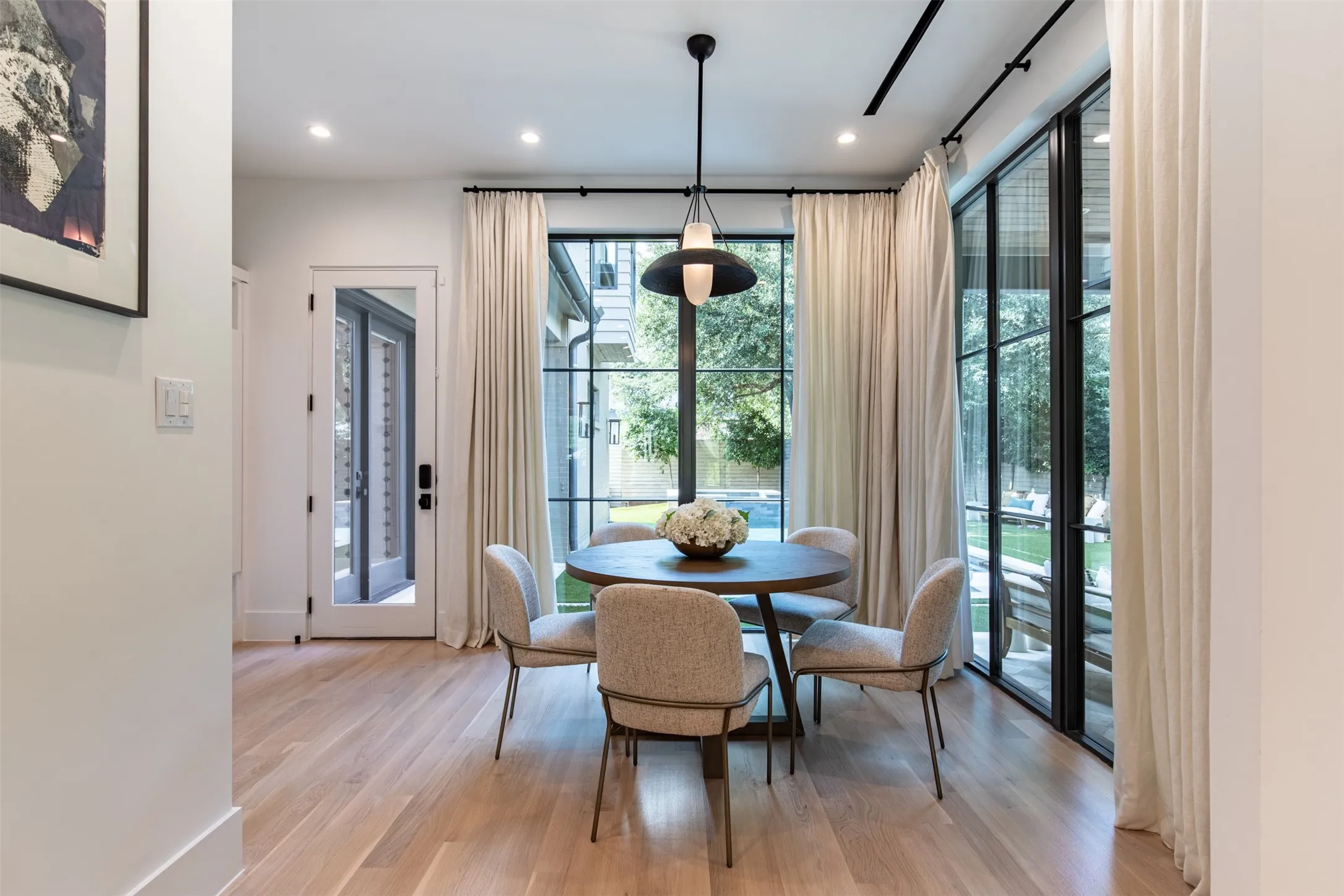 Dining area featuring light wood-finish flooring, recessed lighting, and a modern pendant fixture
