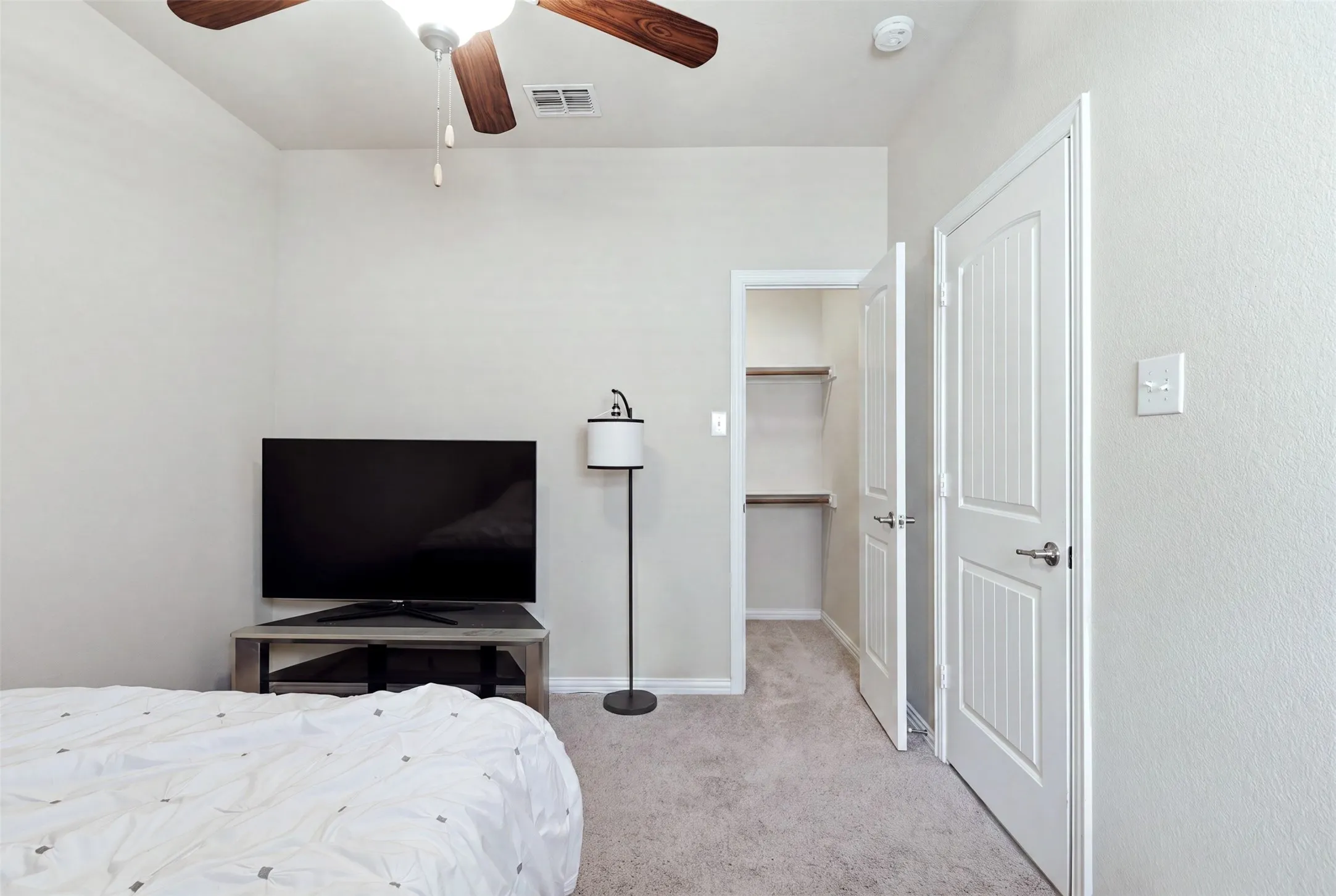 Recessed closet with built-in shelving, white paneled door, and neutral wall color