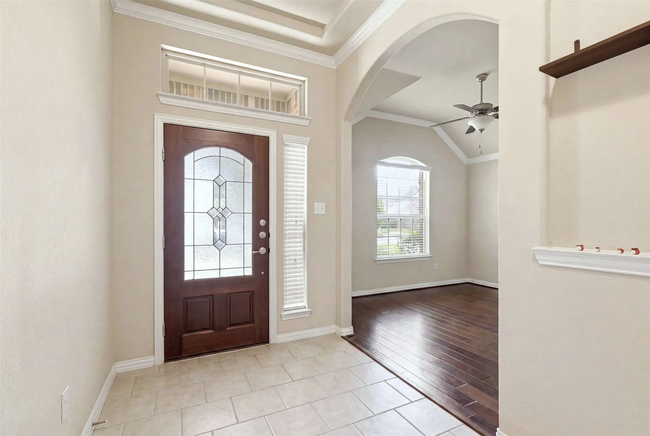 Entryway featuring a wood-finish door with leaded glass, transom window, and tile flooring