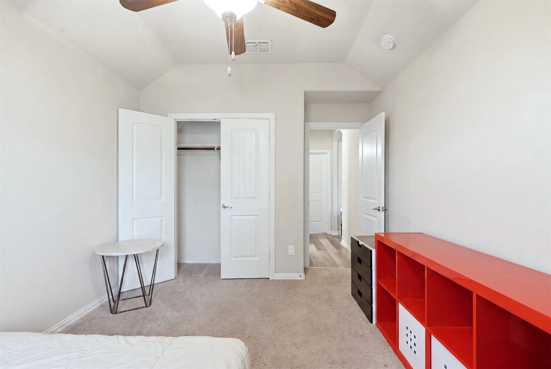 Carpeted room with vaulted ceiling and a ceiling fan