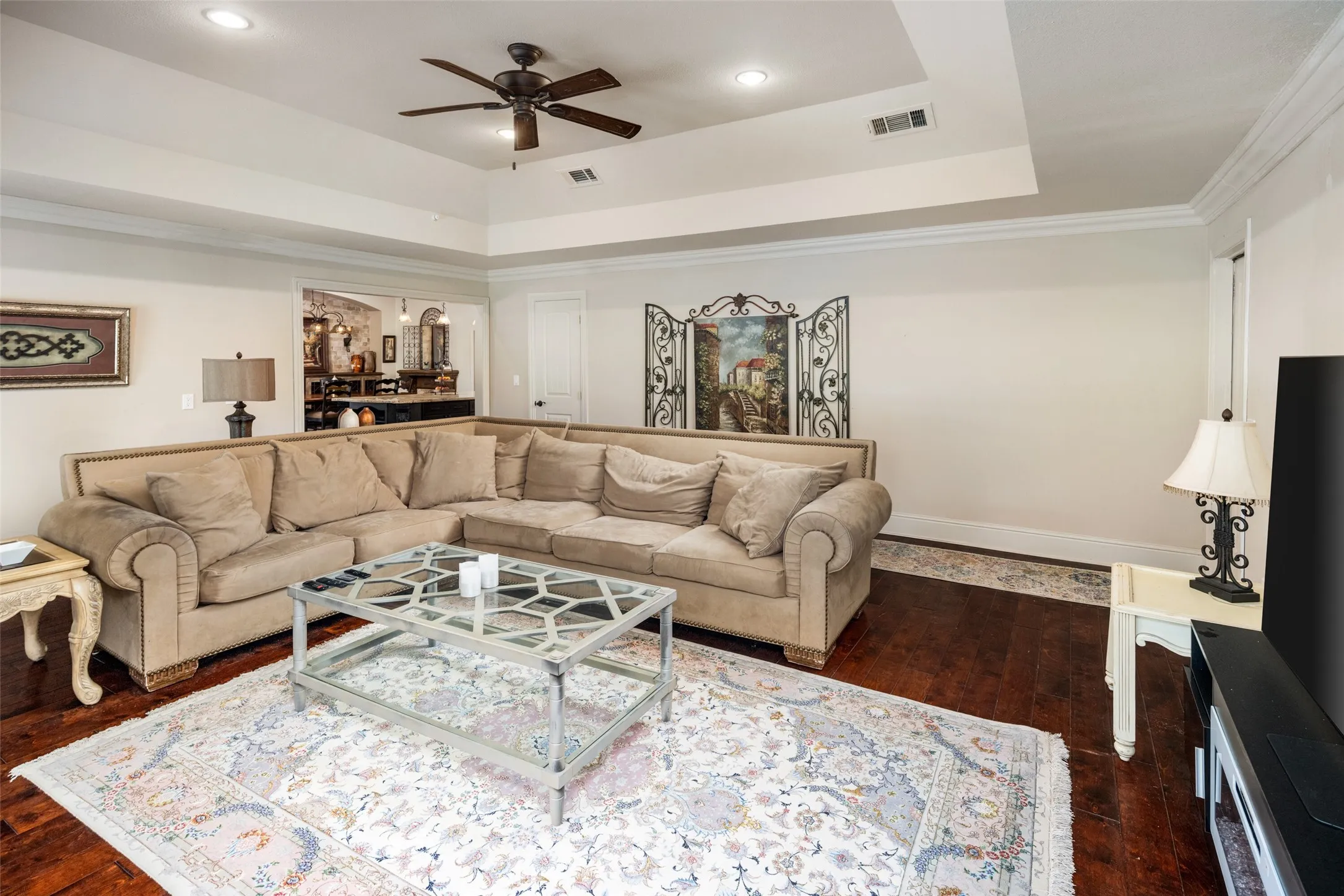 Living area featuring ceiling fan, recessed lighting, a tray ceiling, dark wood-style floors, and crown molding