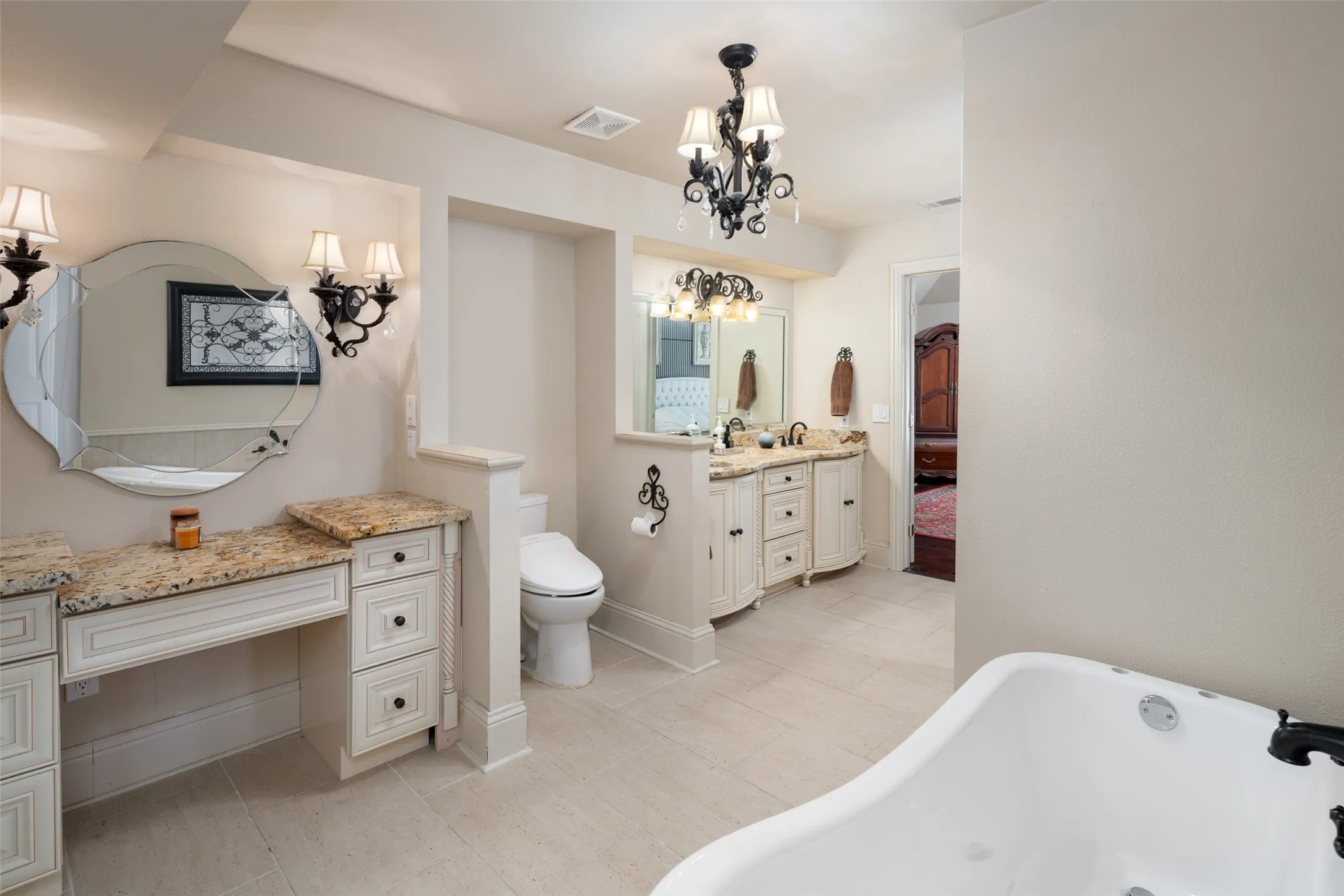 Master bathroom with a chandelier, a freestanding tub, separate vanity,