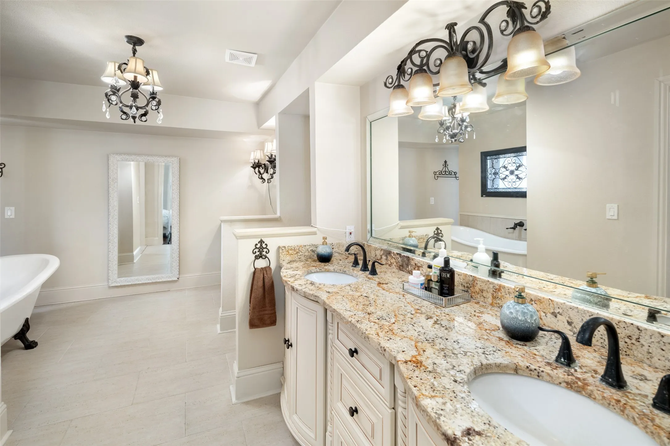 master bath featuring a chandelier, a freestanding tub, double vanity, and baseboards
