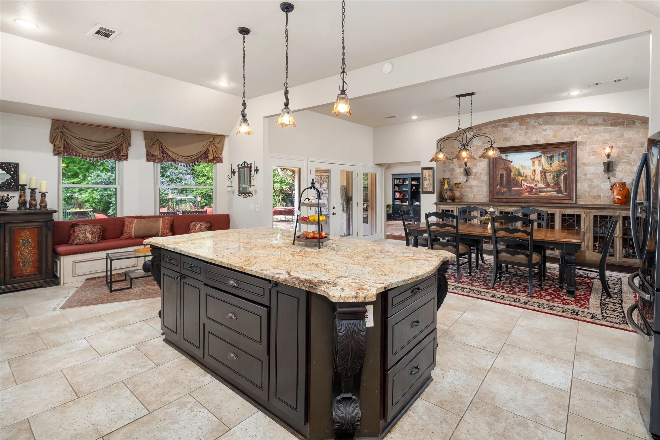 Kitchen with hanging light fixtures, light stone counters, a center island, a chandelier, and light tile patterned floors