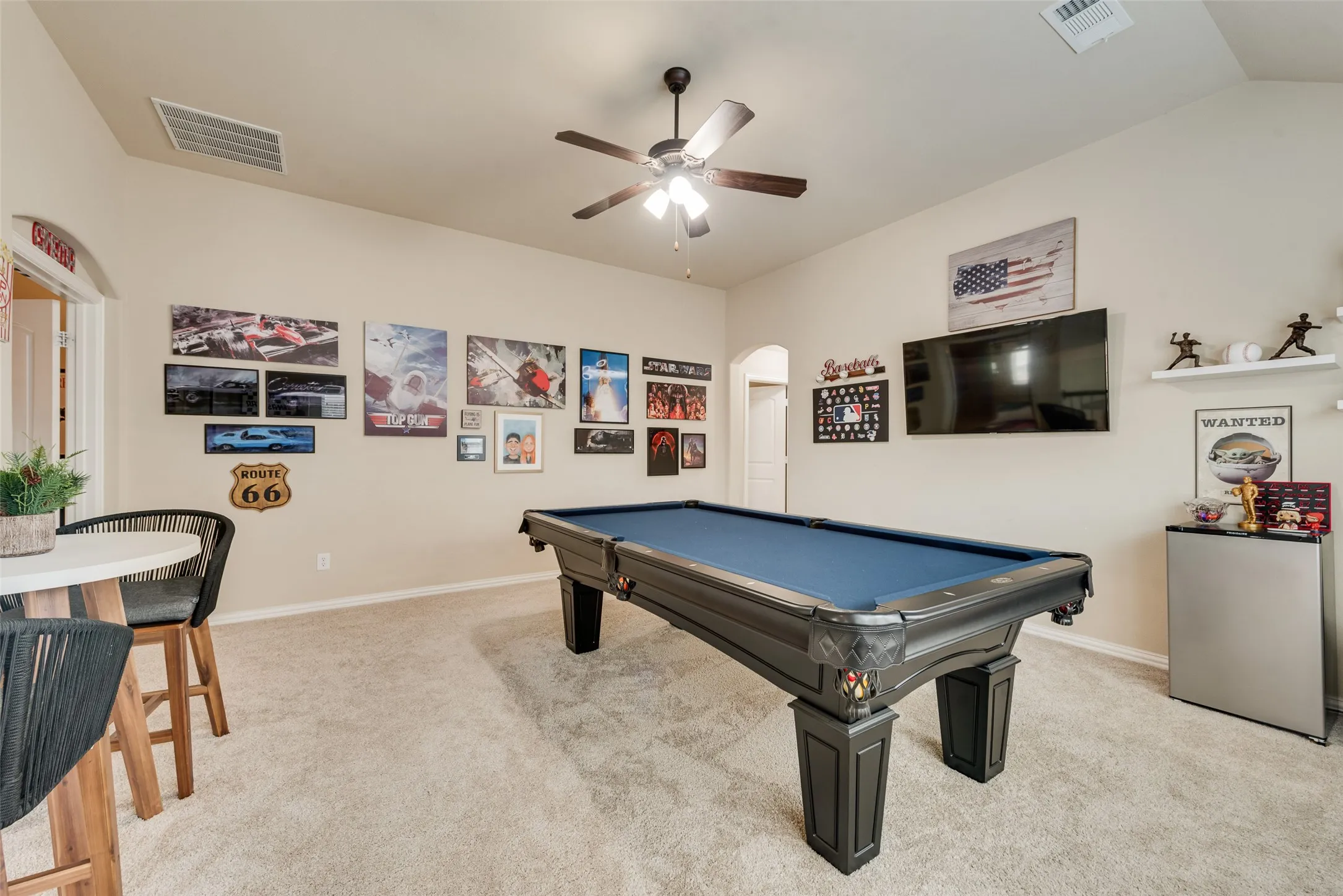 Spacious room featuring vaulted ceilings, neutral-toned carpeting, a ceiling fan, and built-in shelving