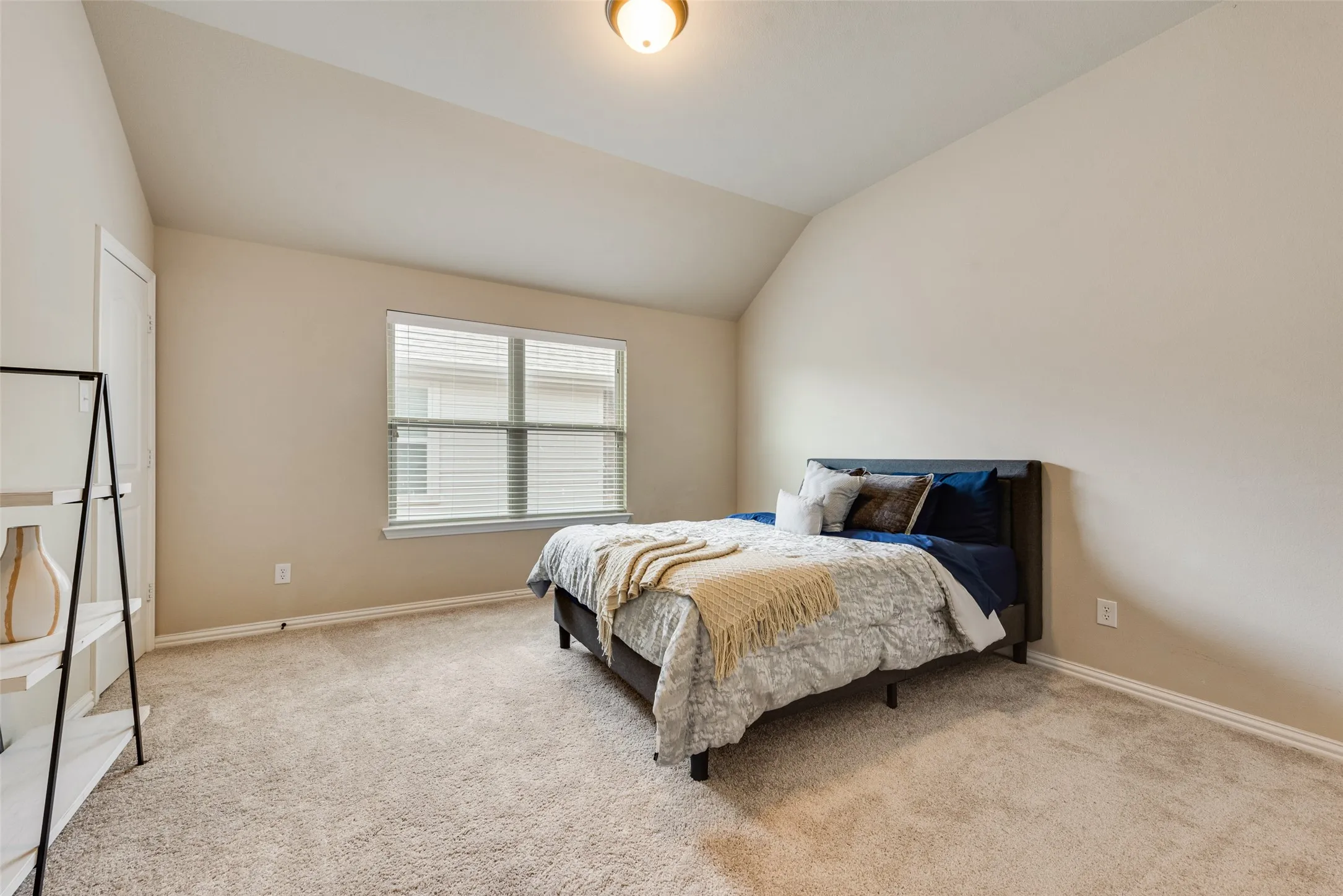 Carpeted room featuring a vaulted ceiling and a rectangular window with blinds