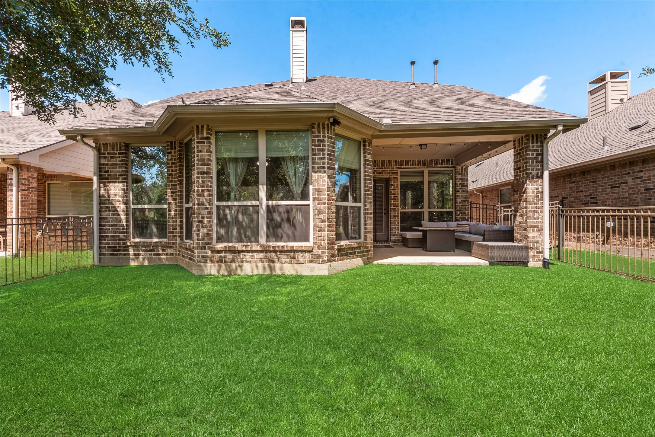 Expansive green lawn bordering a brick exterior with a covered patio