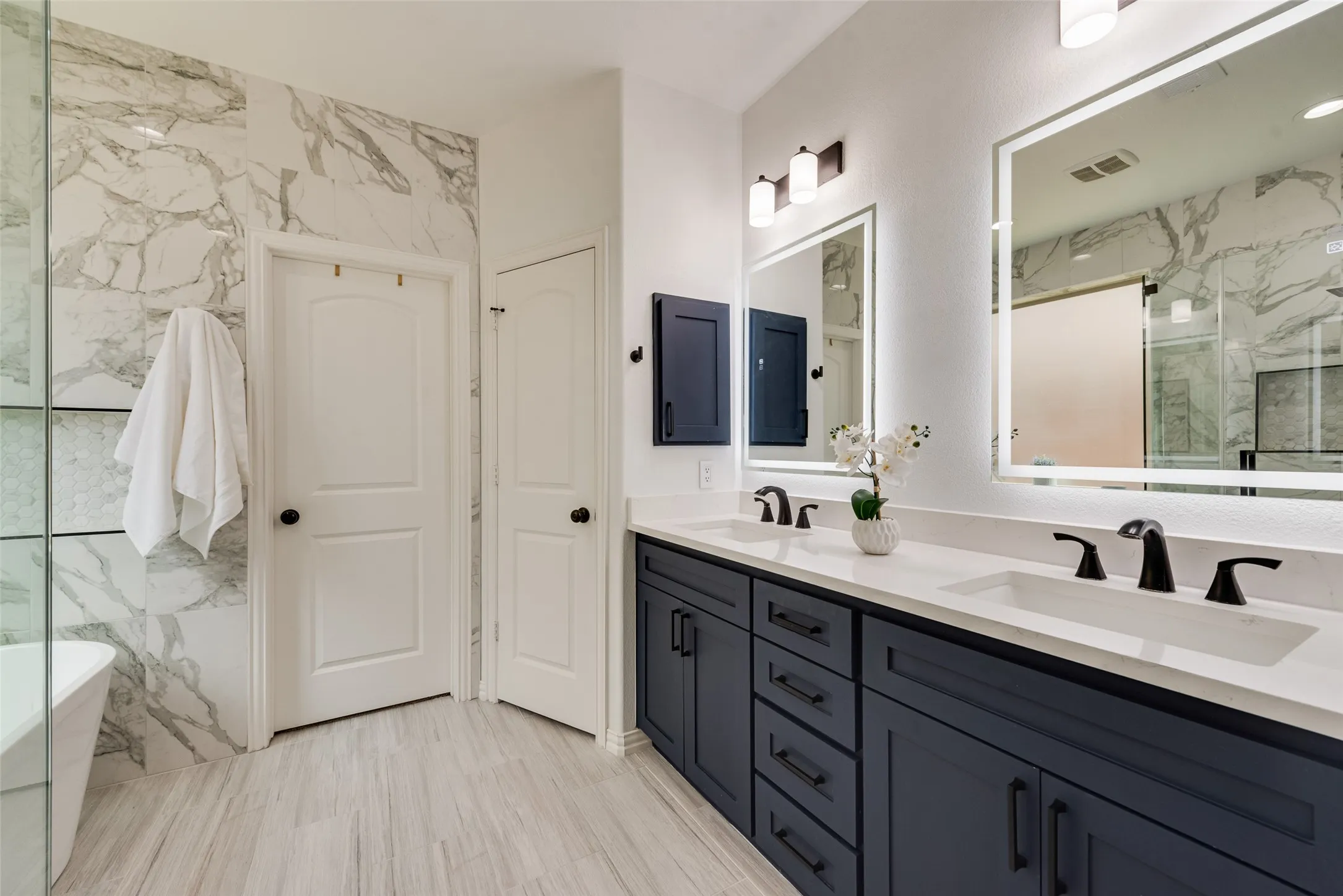 Dual vanity with dark cabinetry and white countertops, featuring integrated sinks and matte black fixtures
