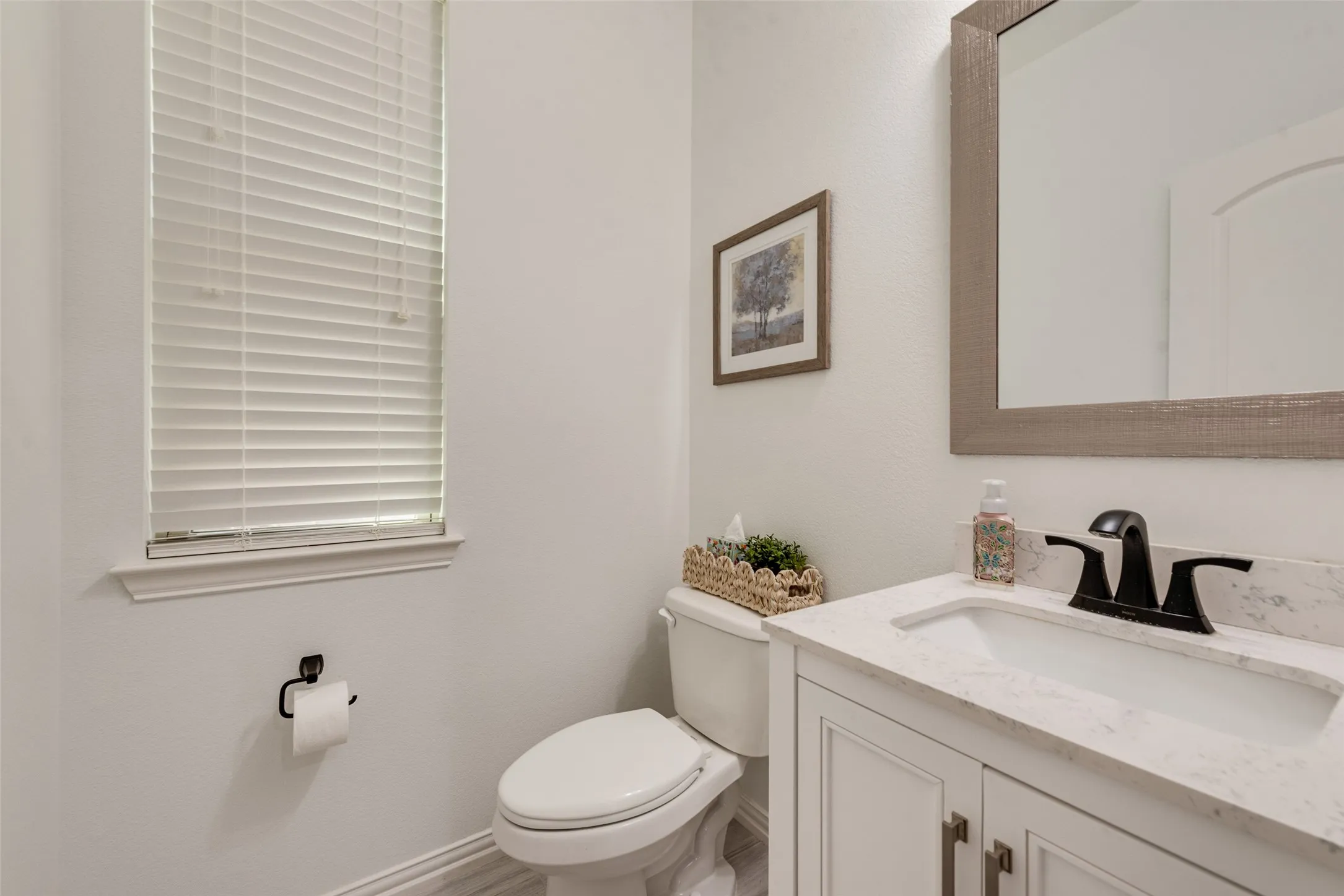 Vanity with white cabinetry, integrated sink, and dark bronze faucet