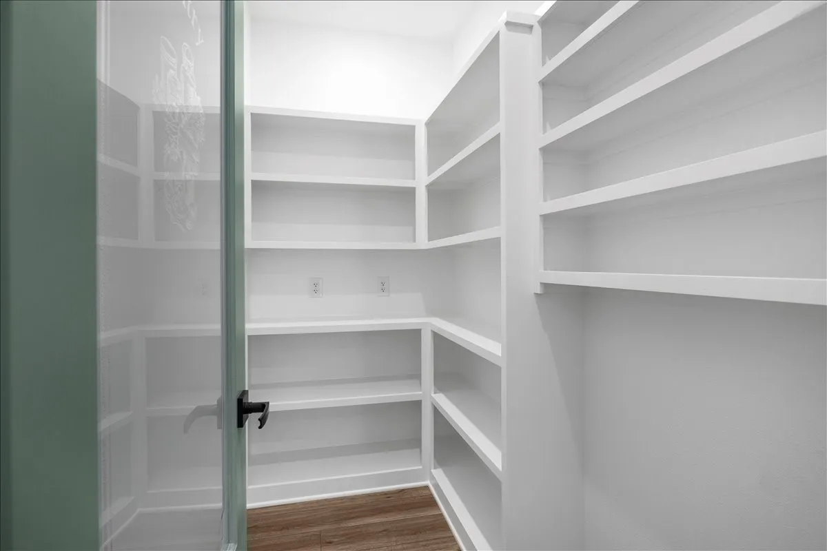 Built-in white shelving, wood-finish flooring, and a glass-paneled door with dark hardware
