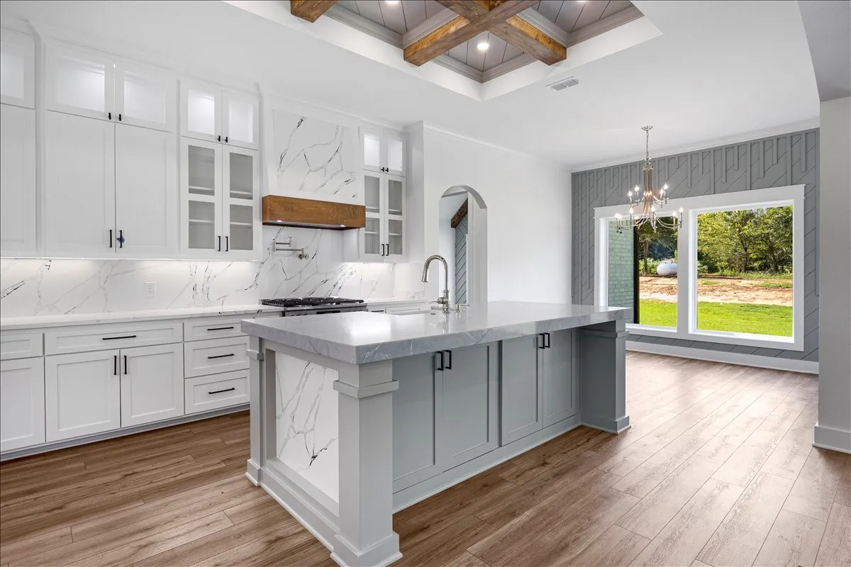Gourmet kitchen with wood-finish flooring, white cabinetry, integrated range, and stone countertops