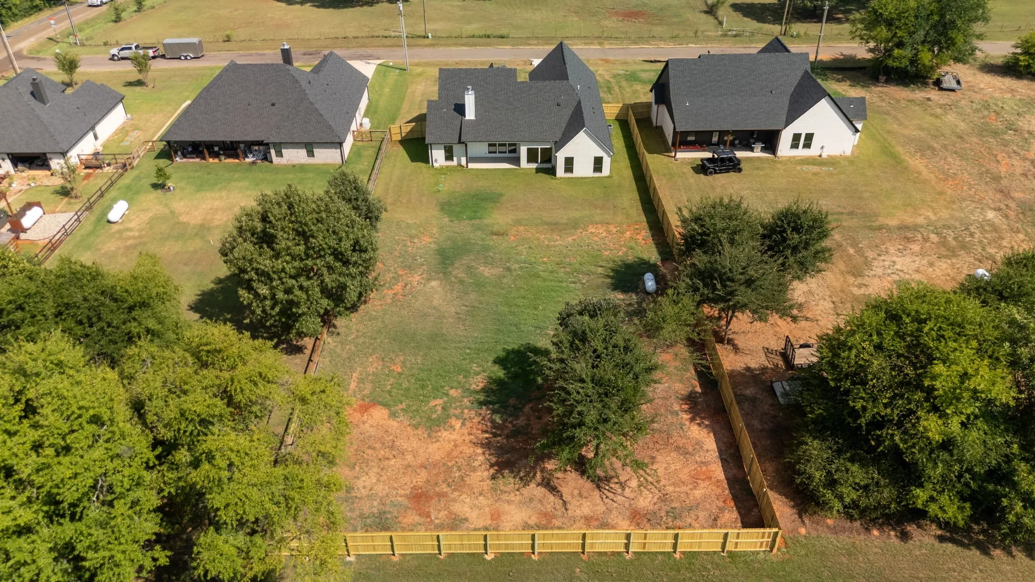 Expansive lot featuring a newly installed wooden fence and mature trees