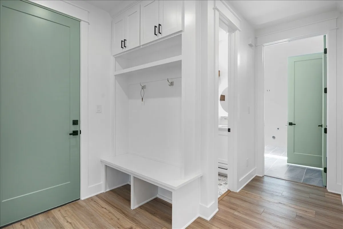Built-in mudroom bench with upper cabinetry, open shelving, and coat hooks